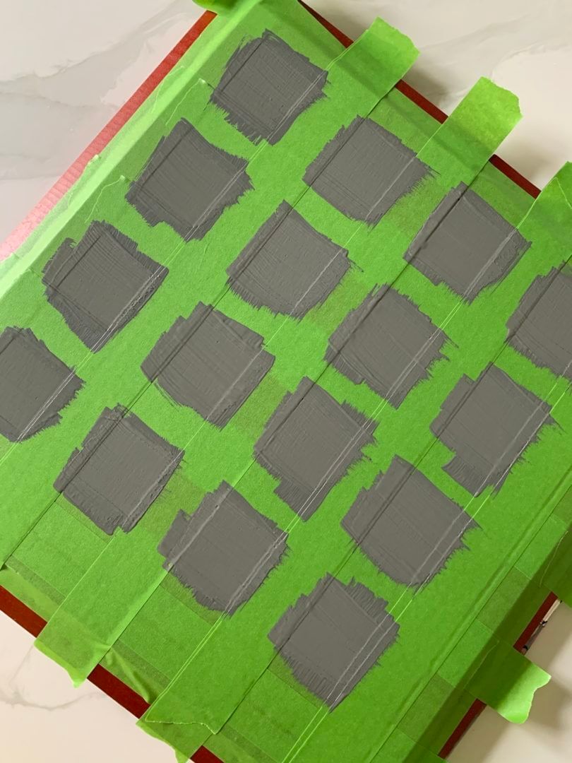 Gray squares painted on a board. the squares are sectioned off with Green FrogTape Multi-Surface Painter's Tape