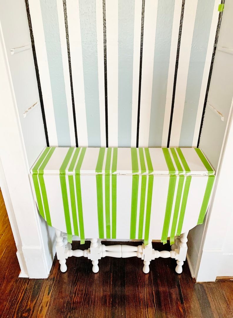 A small white table in a nook, with multiple strips of Green FrogTape Multi-Surface Painter's Tape running vertically across the table top and down the side