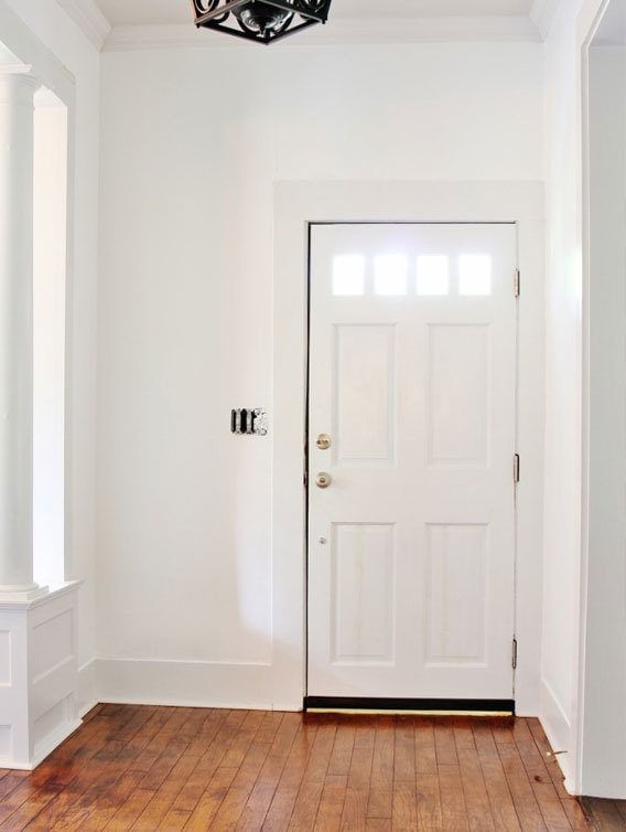 White entryway area with white door and hardwood floor