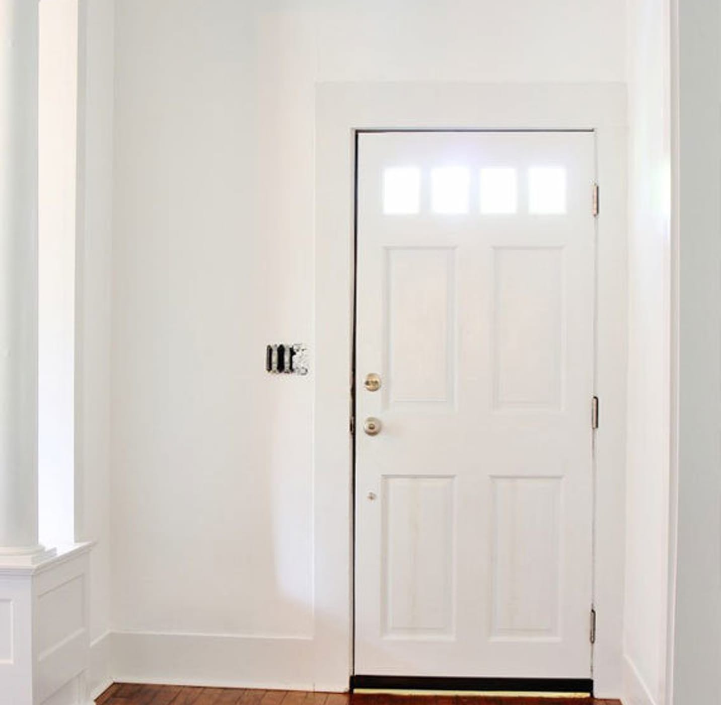 White entryway area with white door and hardwood floor