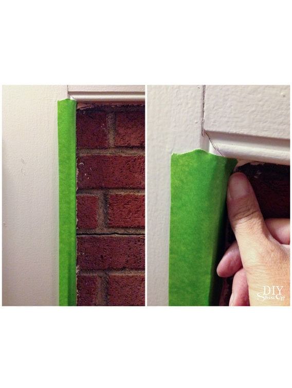 Hand taping off the trim of a brick fireplace with Green FrogTape Multi-Surface Painter's Tape