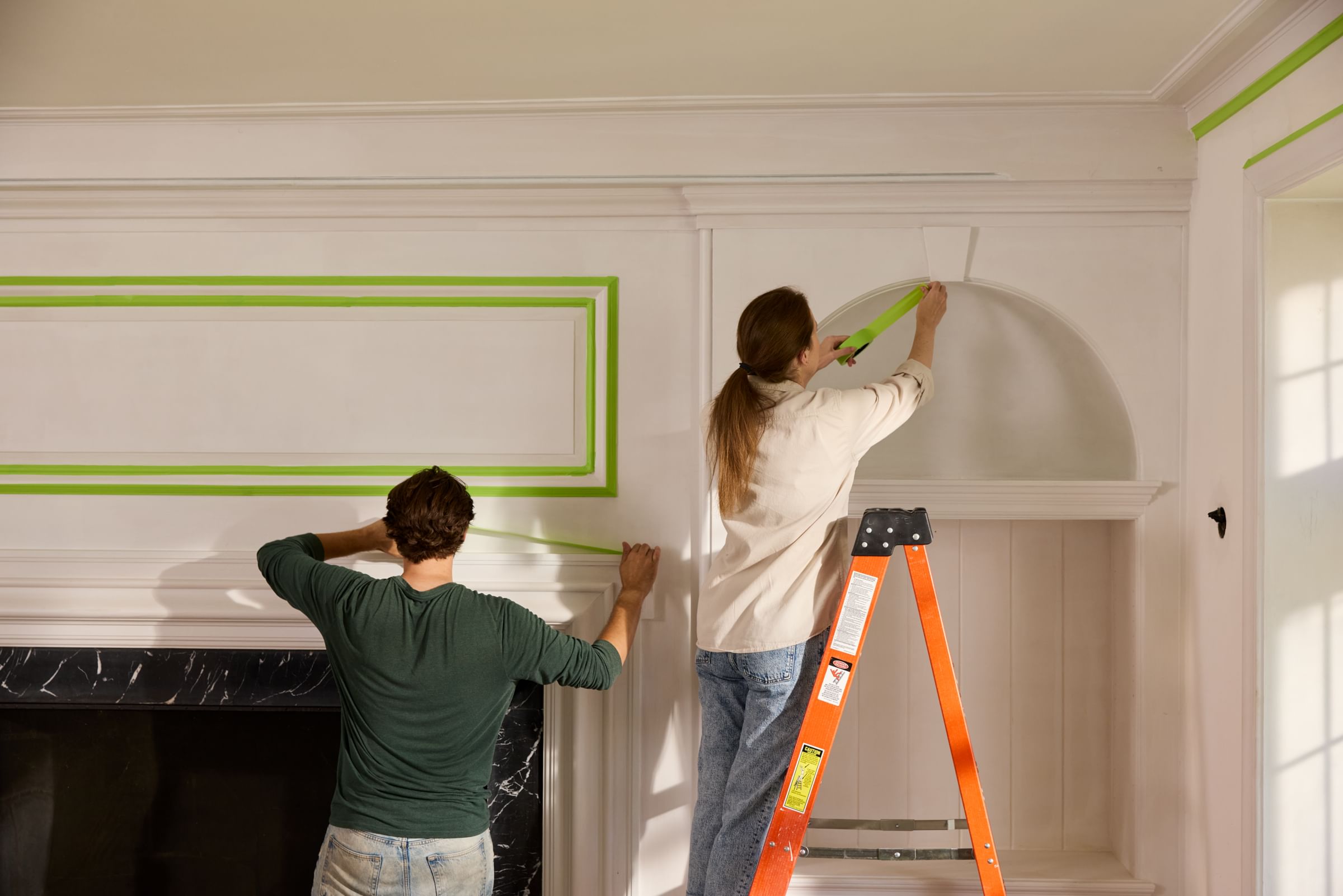 A couple applying Green FrogTape Advanced to a Mantel and Archway
