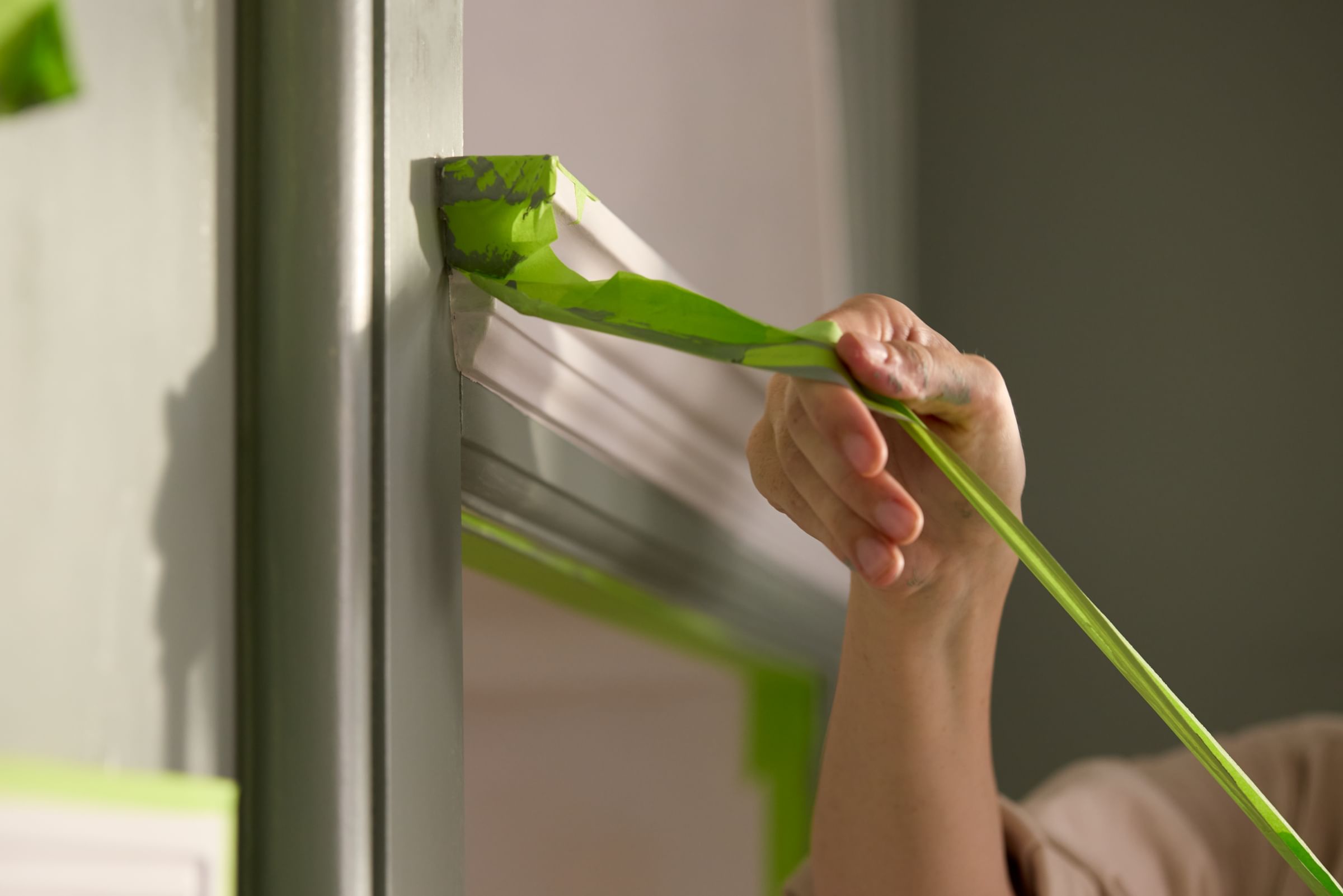 FrogTape Advanced being pulled off of a piece of mantel trim to reveal a crisp line with no paint bleed.