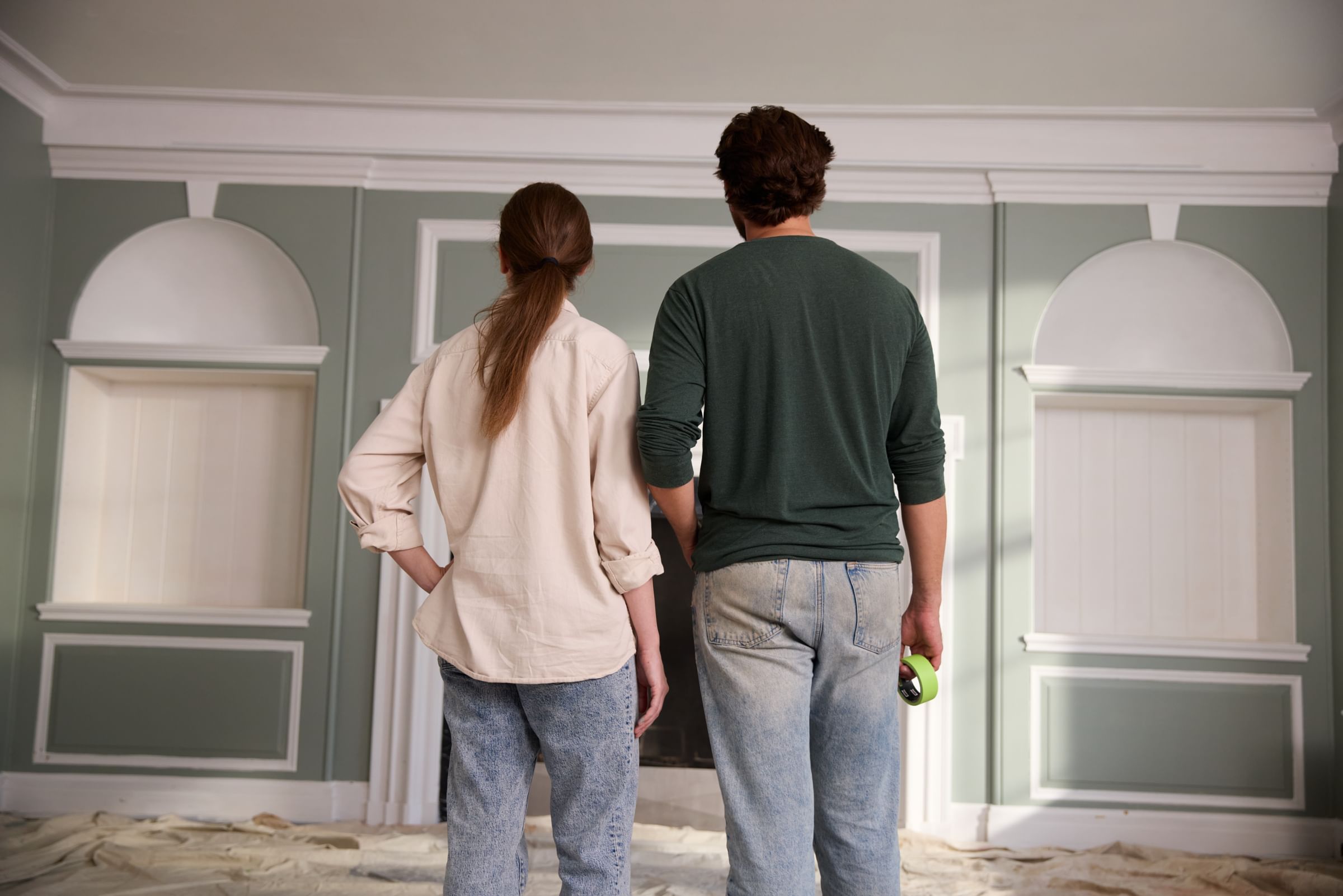 A Couple admiring their freshly painted walls. The man is holding a roll of FrogTape Advanced in his hand.