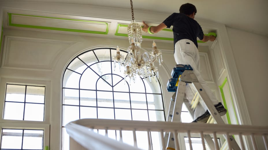 A Paint Contractor on a ladder, Applying FrogTape Advanced Painters Tape