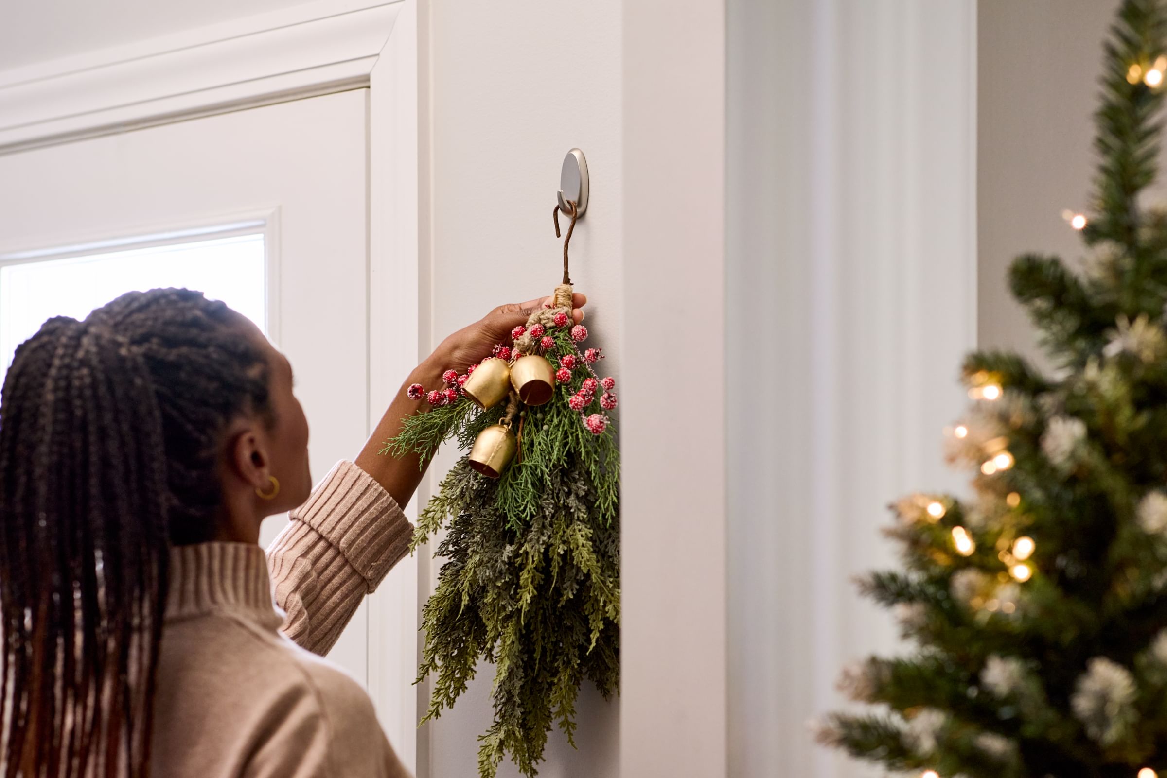 Woman Haning a garland piece from a FrogTape reMOVEables Hook
