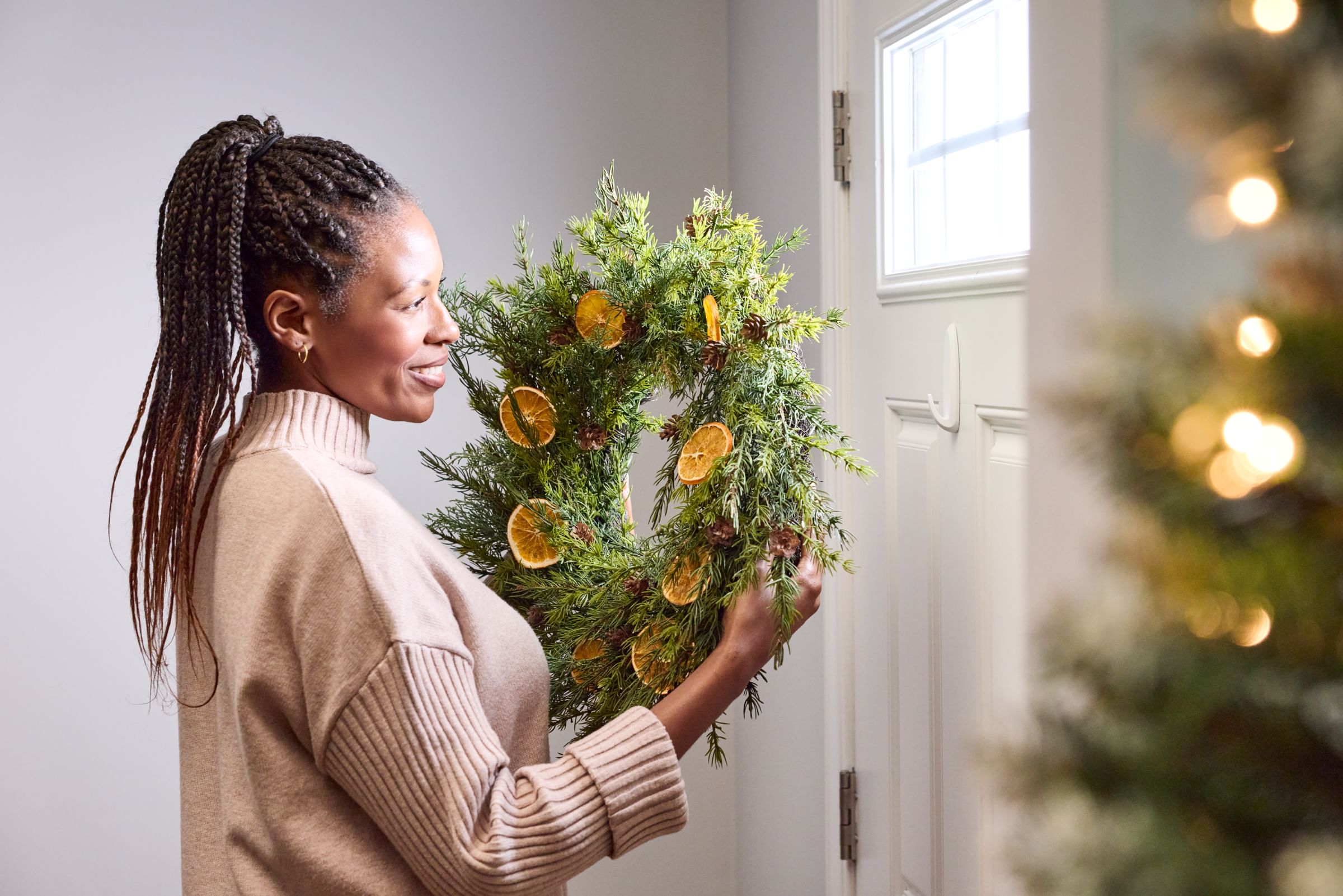 Woman hanging a wreath on her front door using a white FrogTape reMOVEables Hook