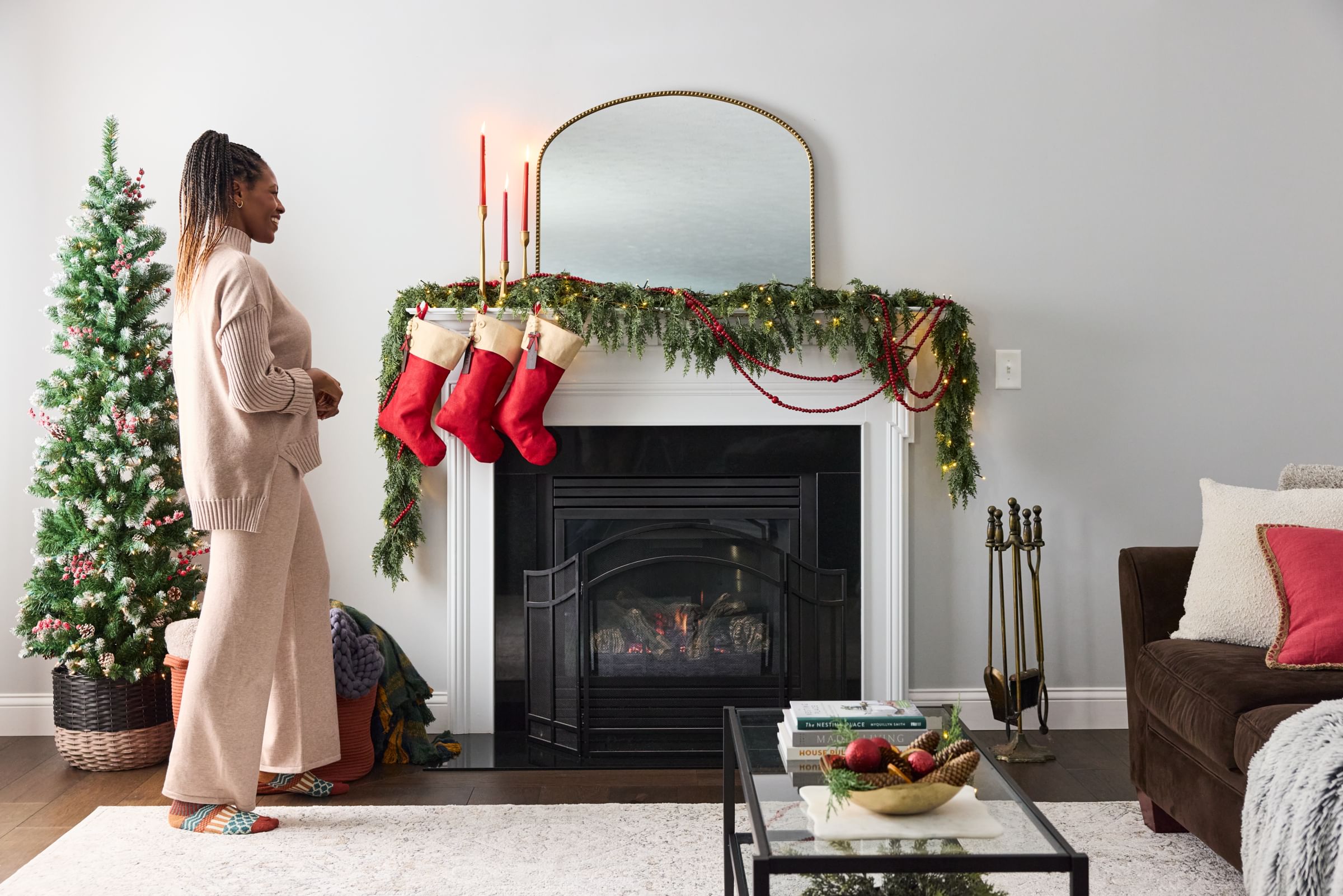A woman looking at her fully decorated Christmas Mantel.