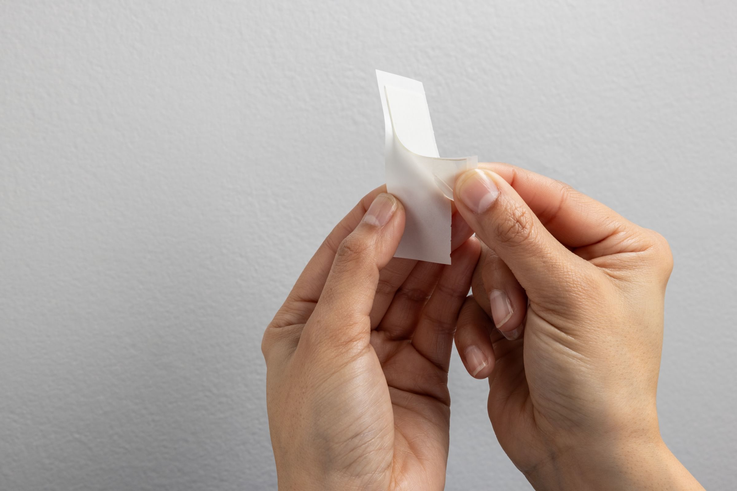 A FrogTape reMOVEables mounting strip being removed from the backing