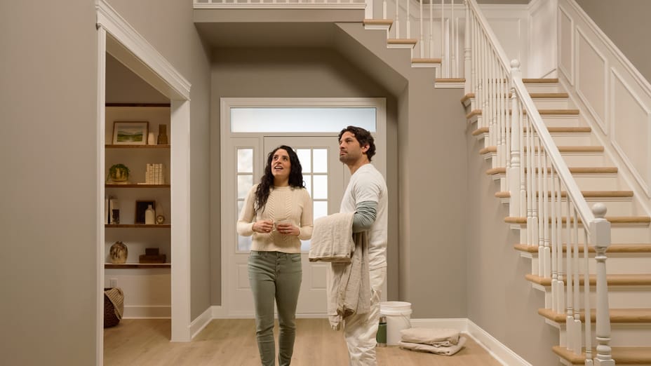 A woman and a painter standing in a freshly painted entryway of a house