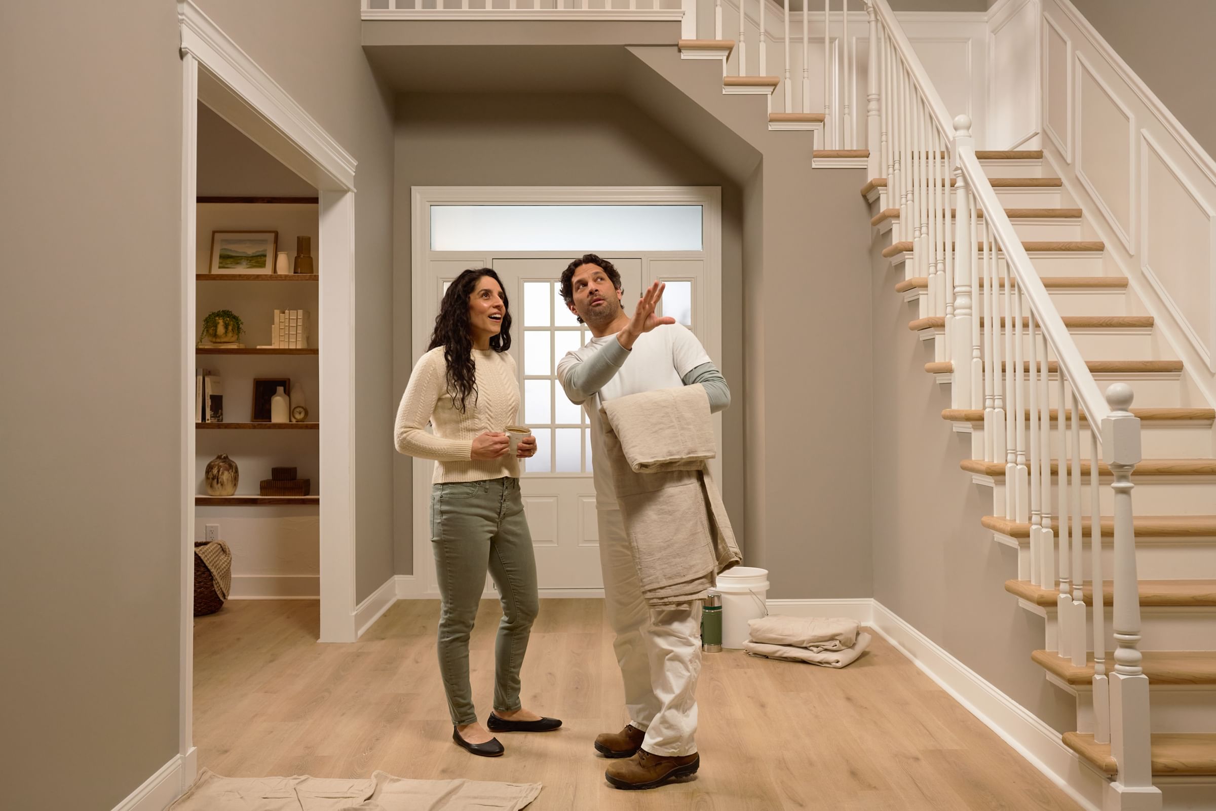 Painter holding a drop cloth talking to client in entry way of home