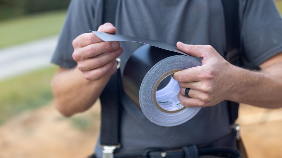 Man holding black roll of FrogTape Flashing Tape