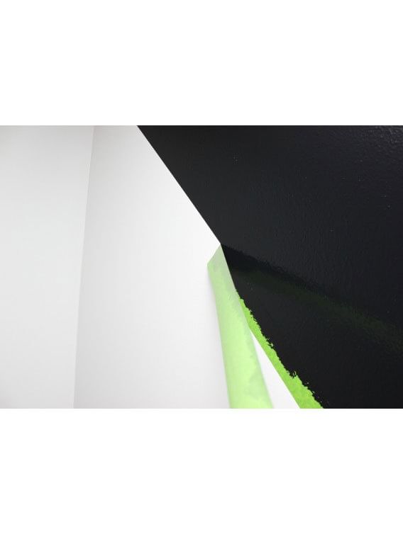 Green FrogTape Multi-Surface Painter's Tape being peeled off of a wall. The tape is creating a crisp line on a wall between the black and white side of the wall.