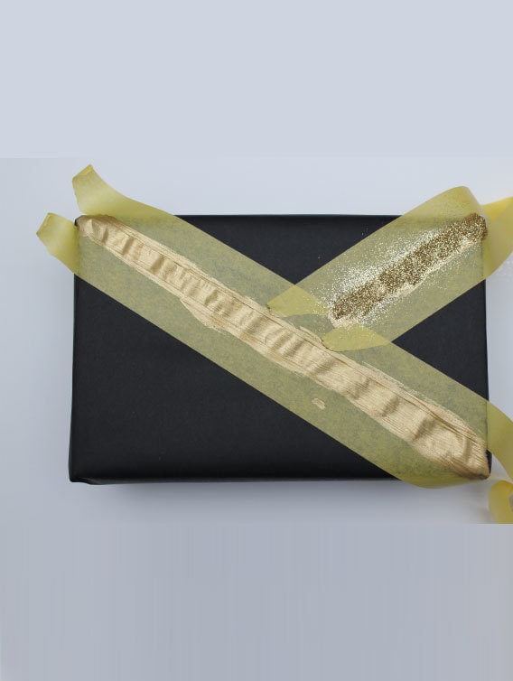 Little black rectangular box with Yellow FrogTape Delicate Surface Painter's Tape on it with light colored paint between the tape