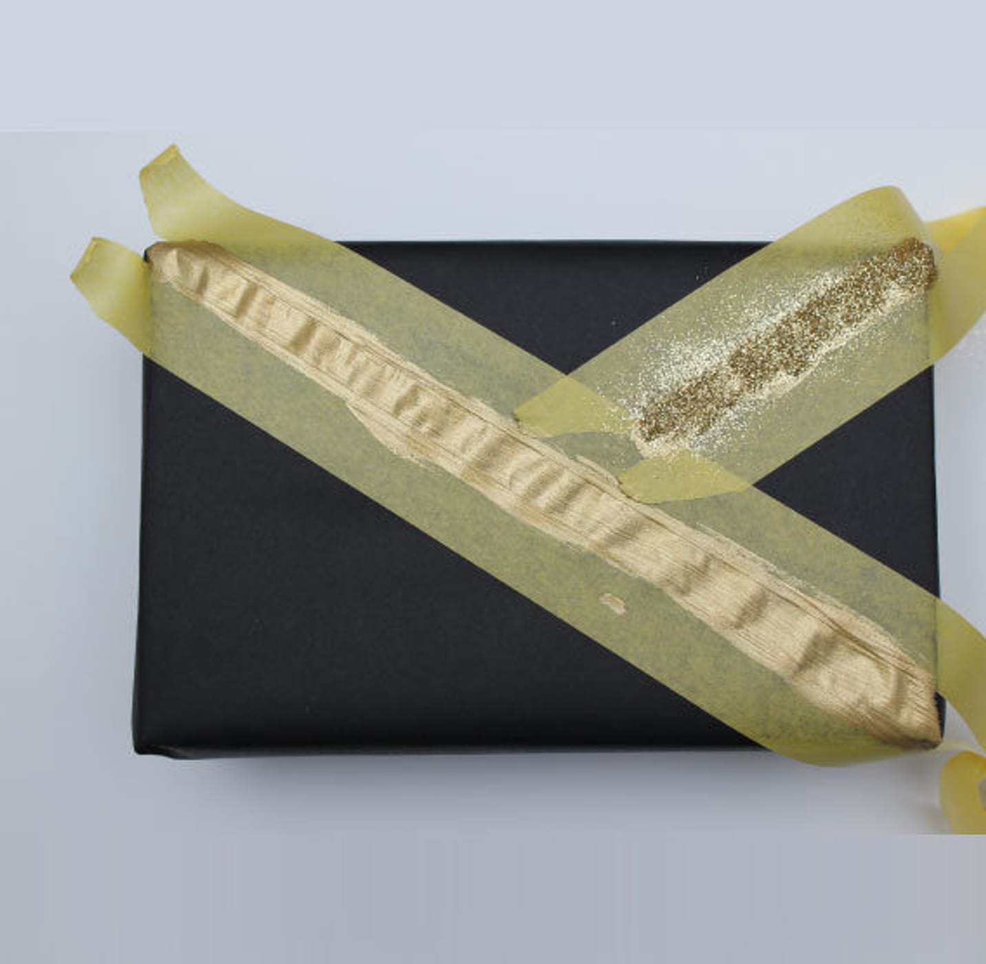 Little black rectangular box with Yellow FrogTape Delicate Surface Painter's Tape on it with light colored paint between the tape