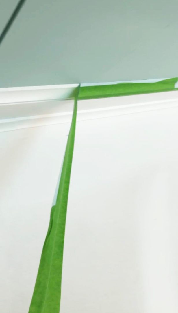 Green FrogTape Multi-Surface Painter's Tape being peeled off of white trim.