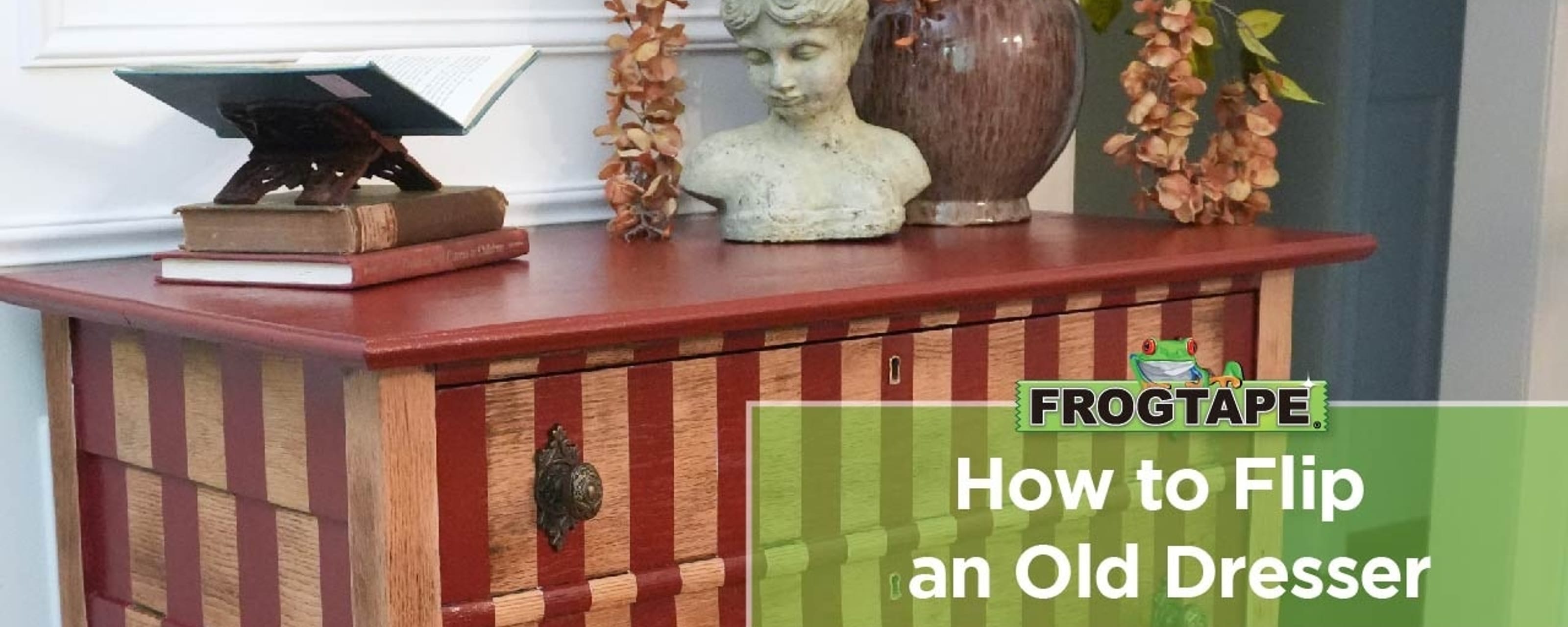 How to Flip an Old Dresser. A red and oak striped dresser with a flower pot, statue bust, and some books on top.