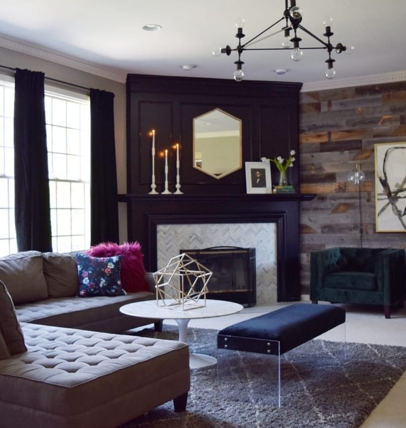 Living room with wraparound couch, round coffee table, two black chairs and fireplace.