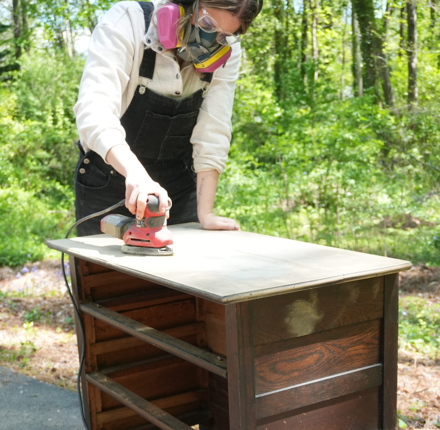 Woman Sanding an old wooden dresser