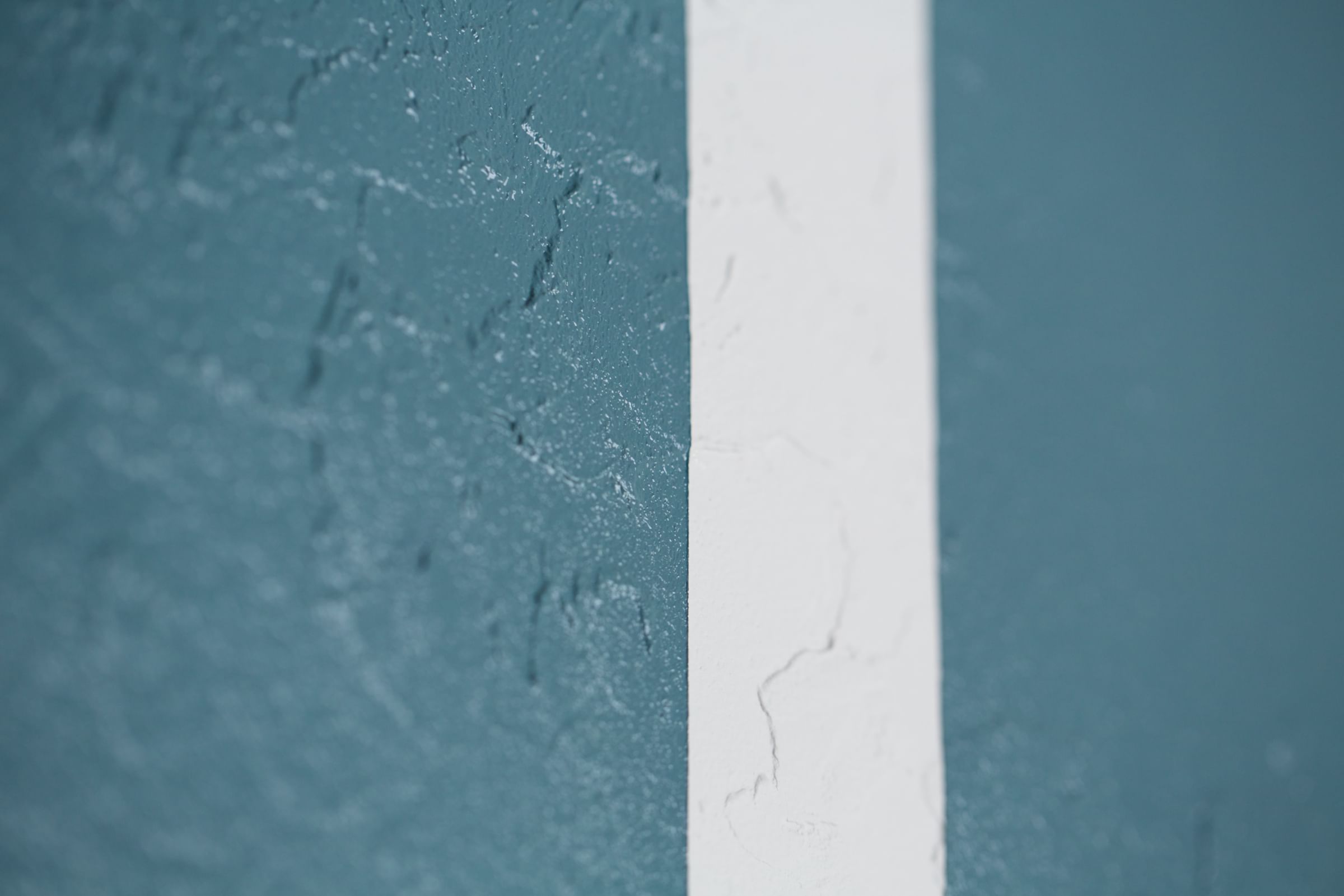 White Line of paint on a blue/gray colored Rough textured Wall