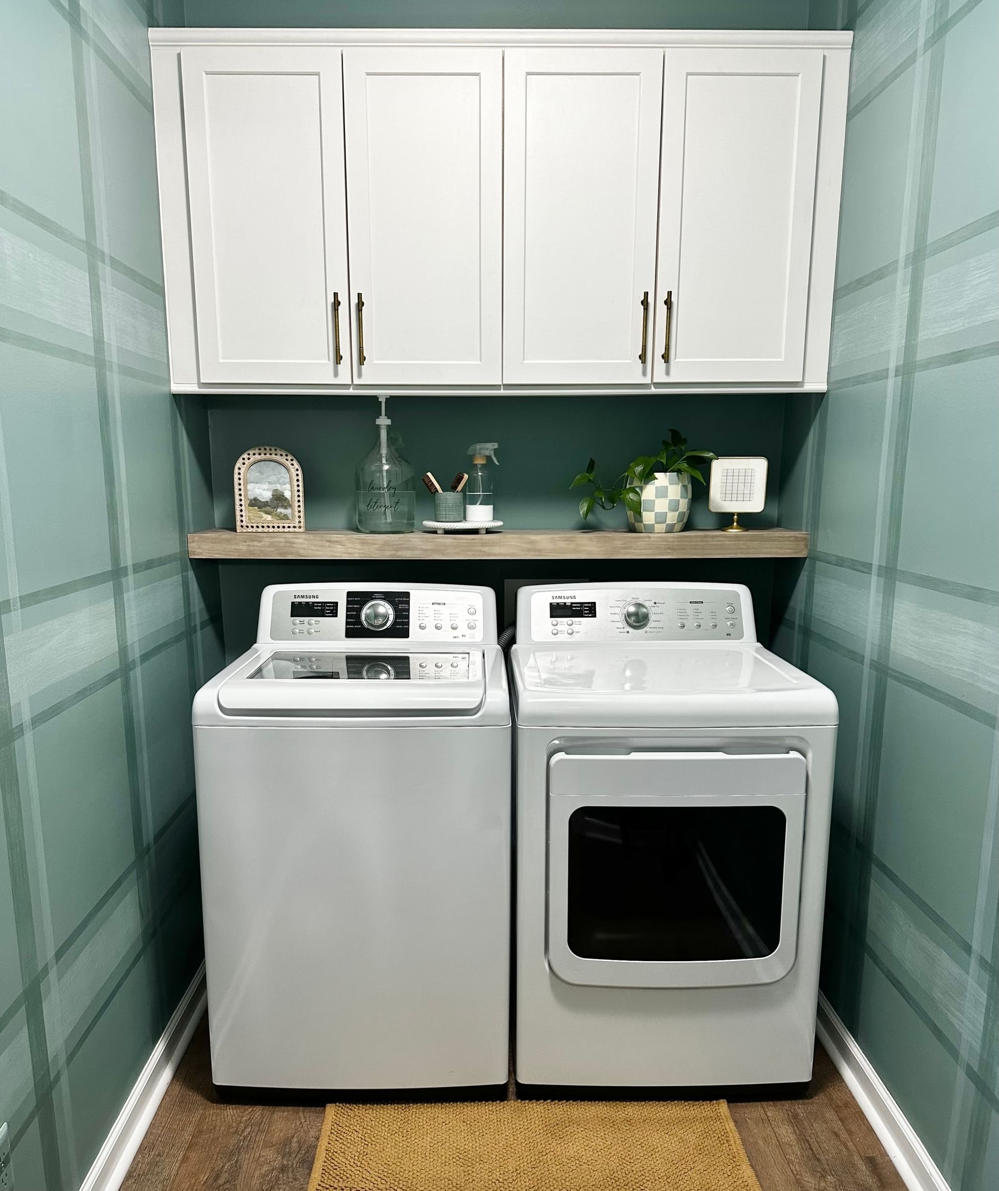 Modern Laundry Room with Washer, Dryer, shelf above, and upper cabinets. The walls are blue/green with a plaid pattern