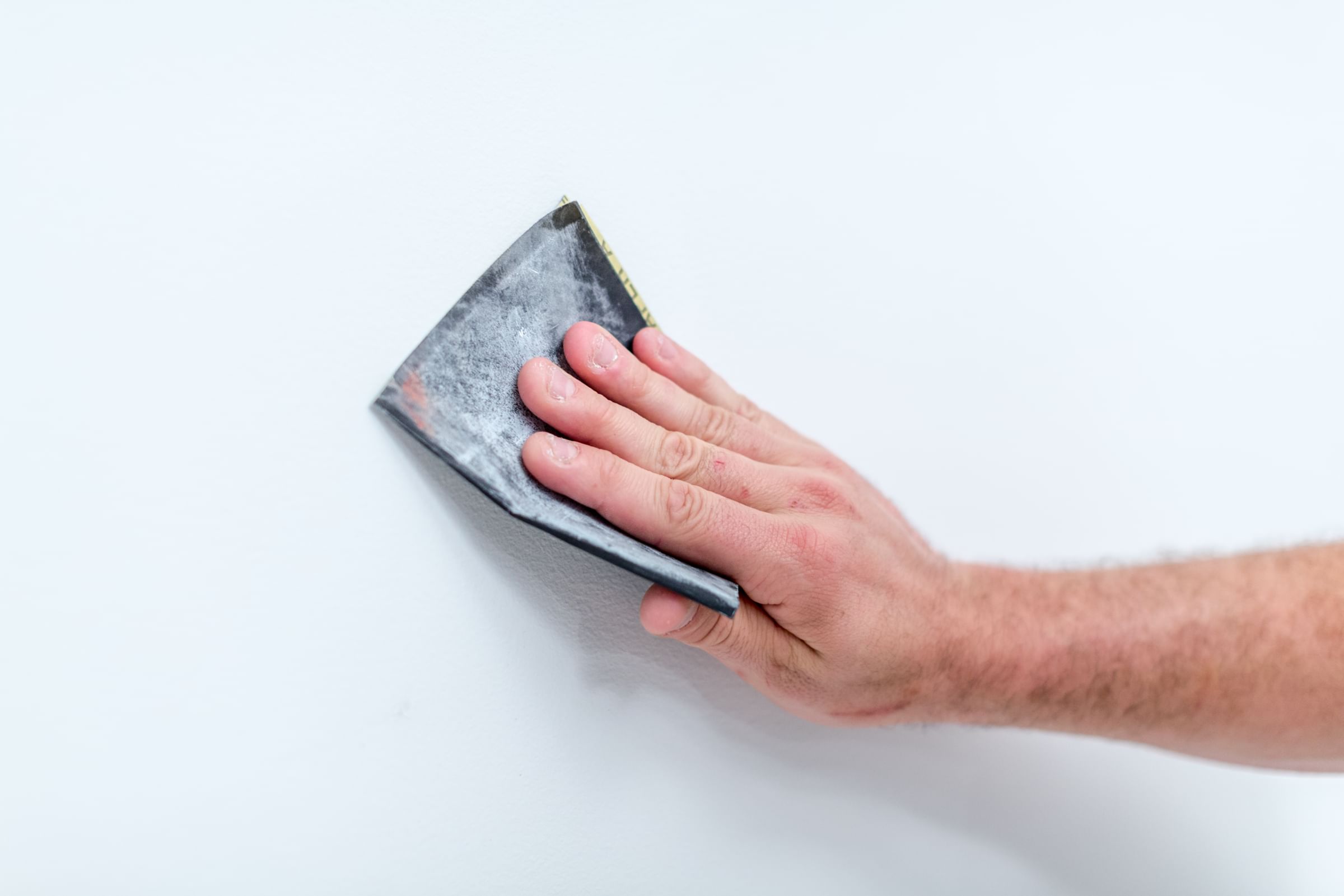 A hand with a rag cleaning a wall