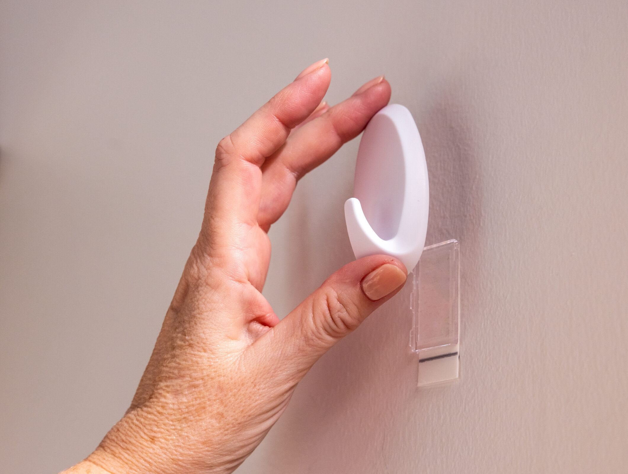 A White FrogTape reMOVEables hook being installed on a wall