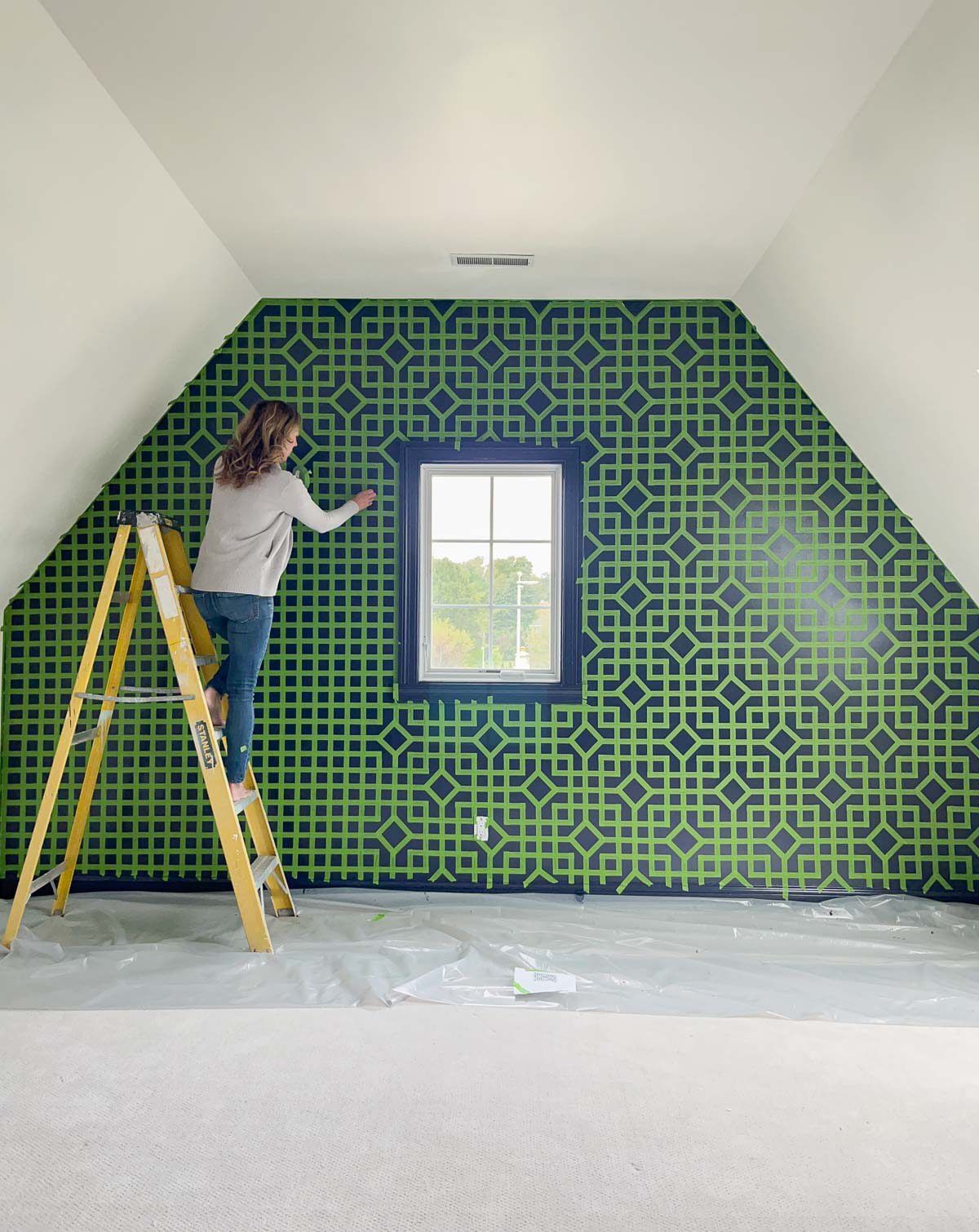 Step 7: Women taping off green wall in geometric pattern
