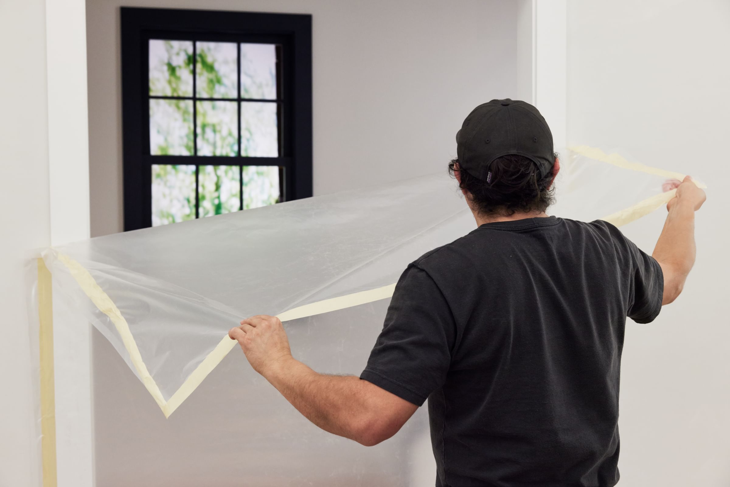A man taking the plastic sheeting with FrogTape DS 154 off of the wall of a doorway