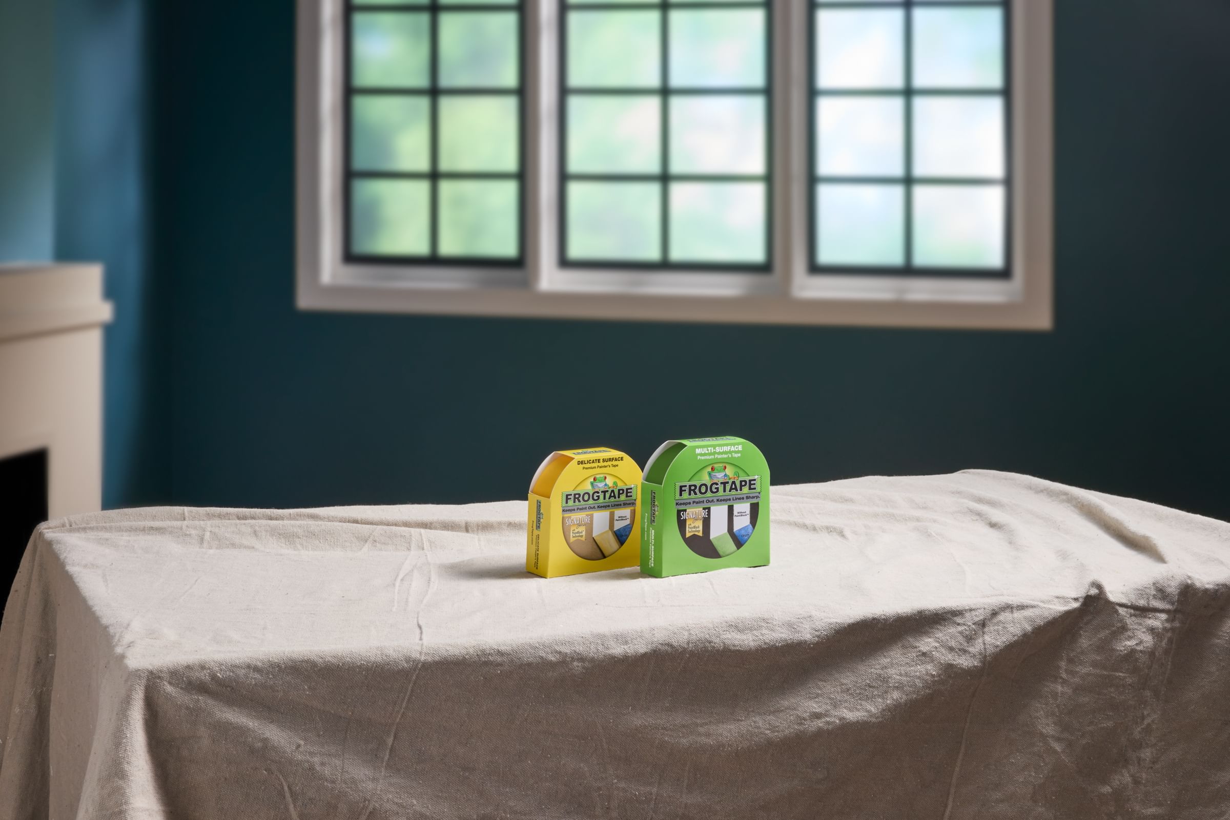 Green FrogTape Multisurface and Yellow FrogTape Delicate Surface Painter's Tapes sitting on a drop cloth on a table