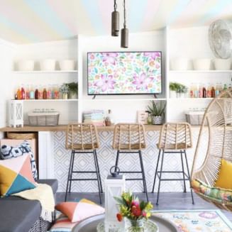 A living room areas looking into a bar area with three bar stools with wicker backs,