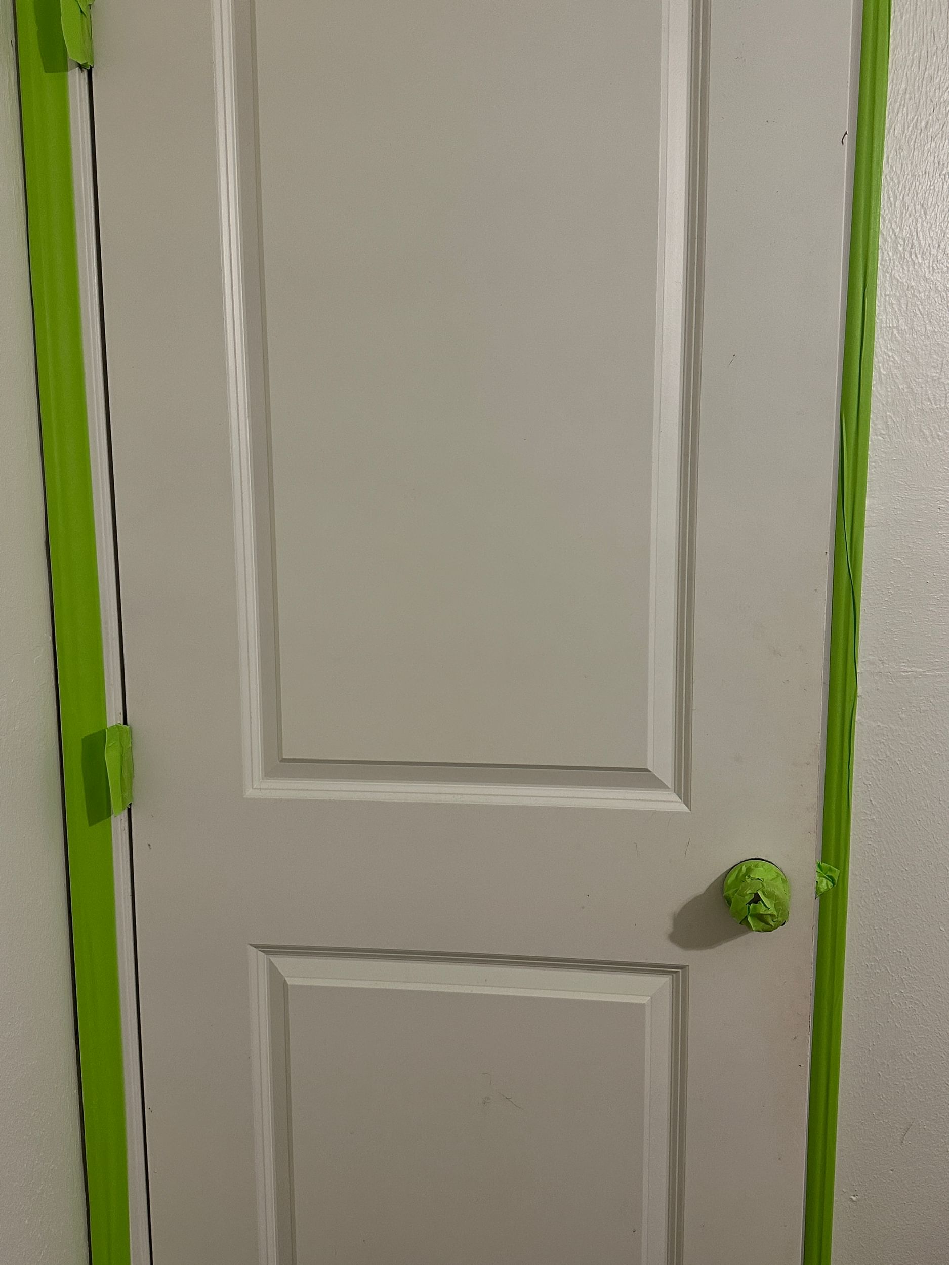 White door with the door knob, hinges, and trim taped off with FrogTape Advanced