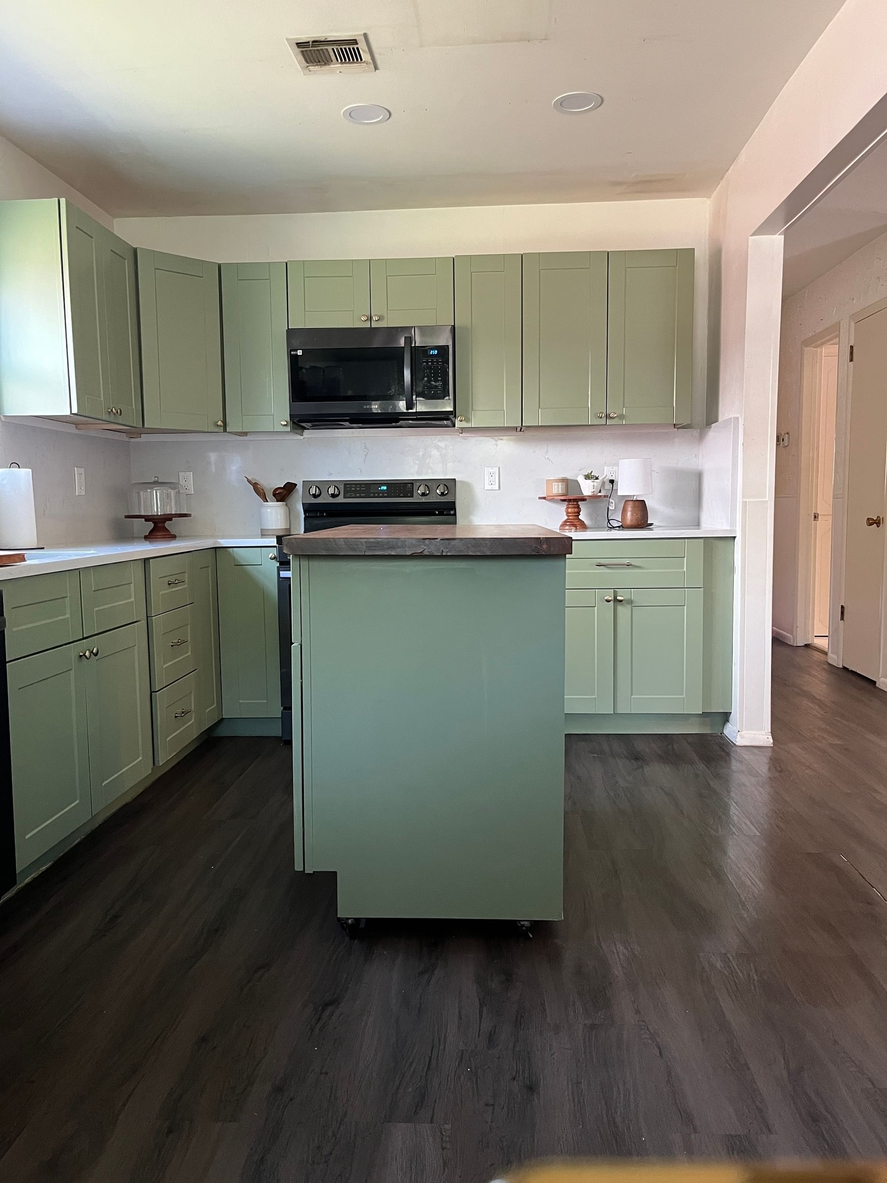 A modern kitchen with olive green color cabinets and island