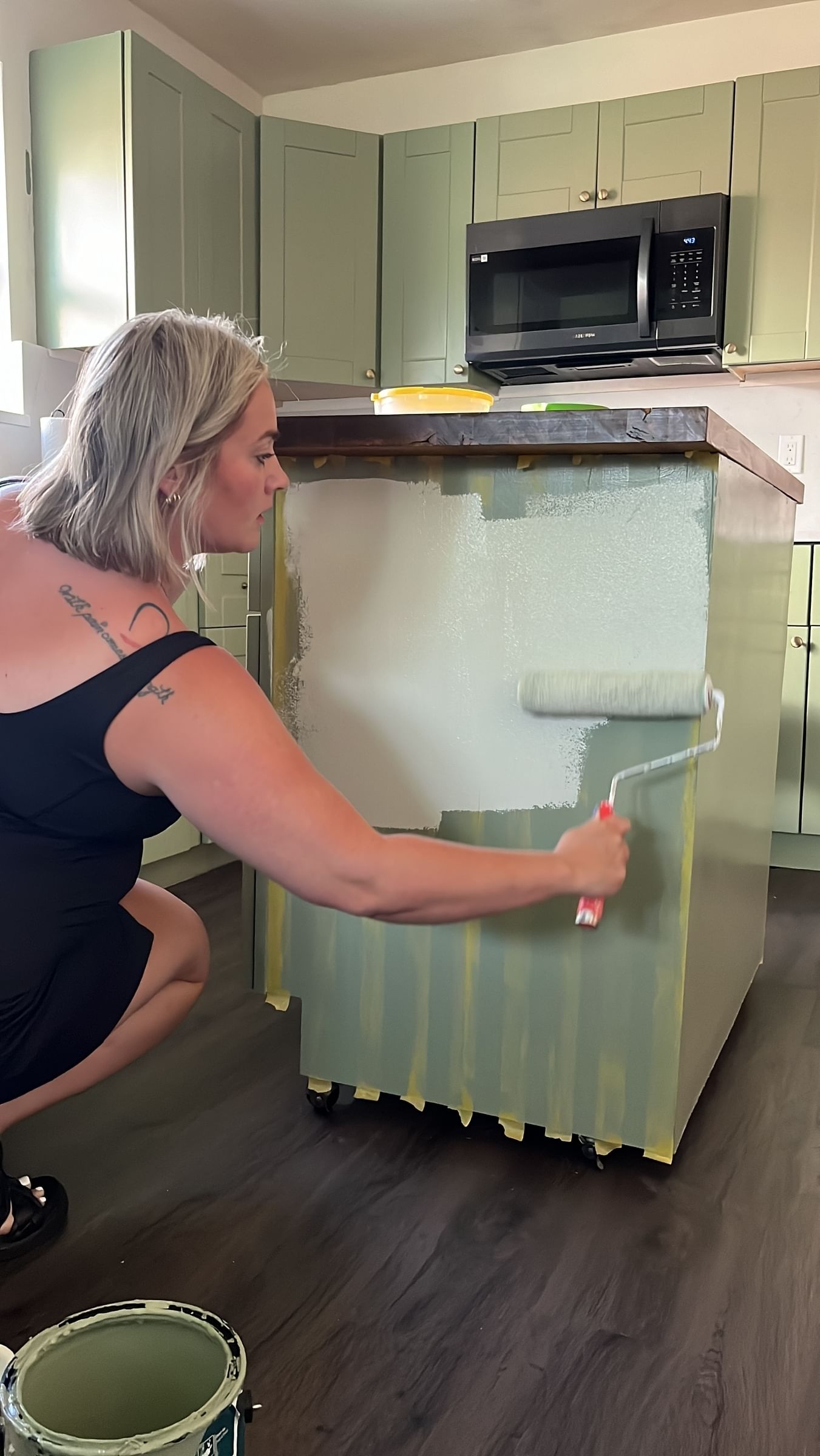 Jess Smith painting a kitchen island green with a paint roller