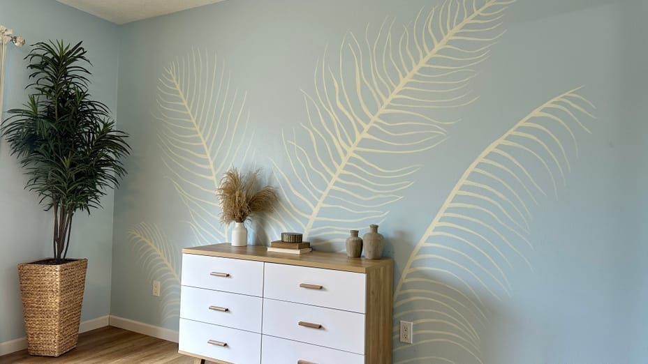 White Palm Leaves Mural on a blue wall with a small dresser
