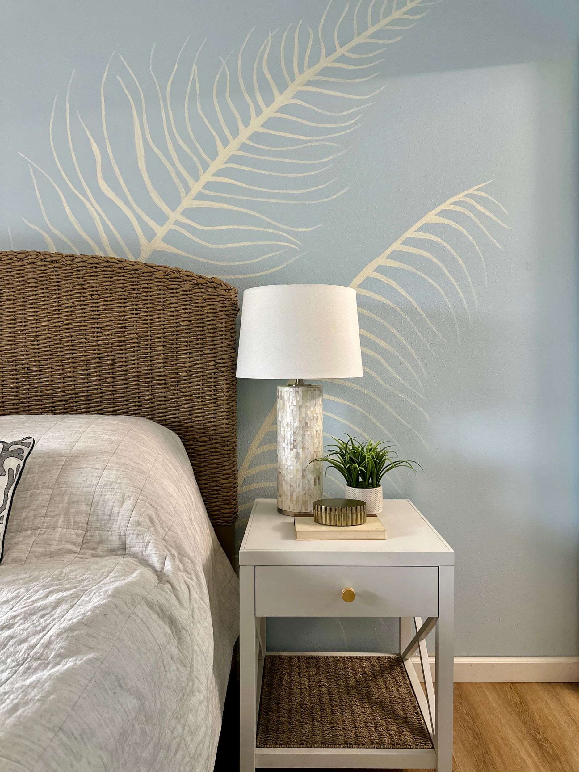 White Palm Leaves Mural on blue wall behind wed and nightstand