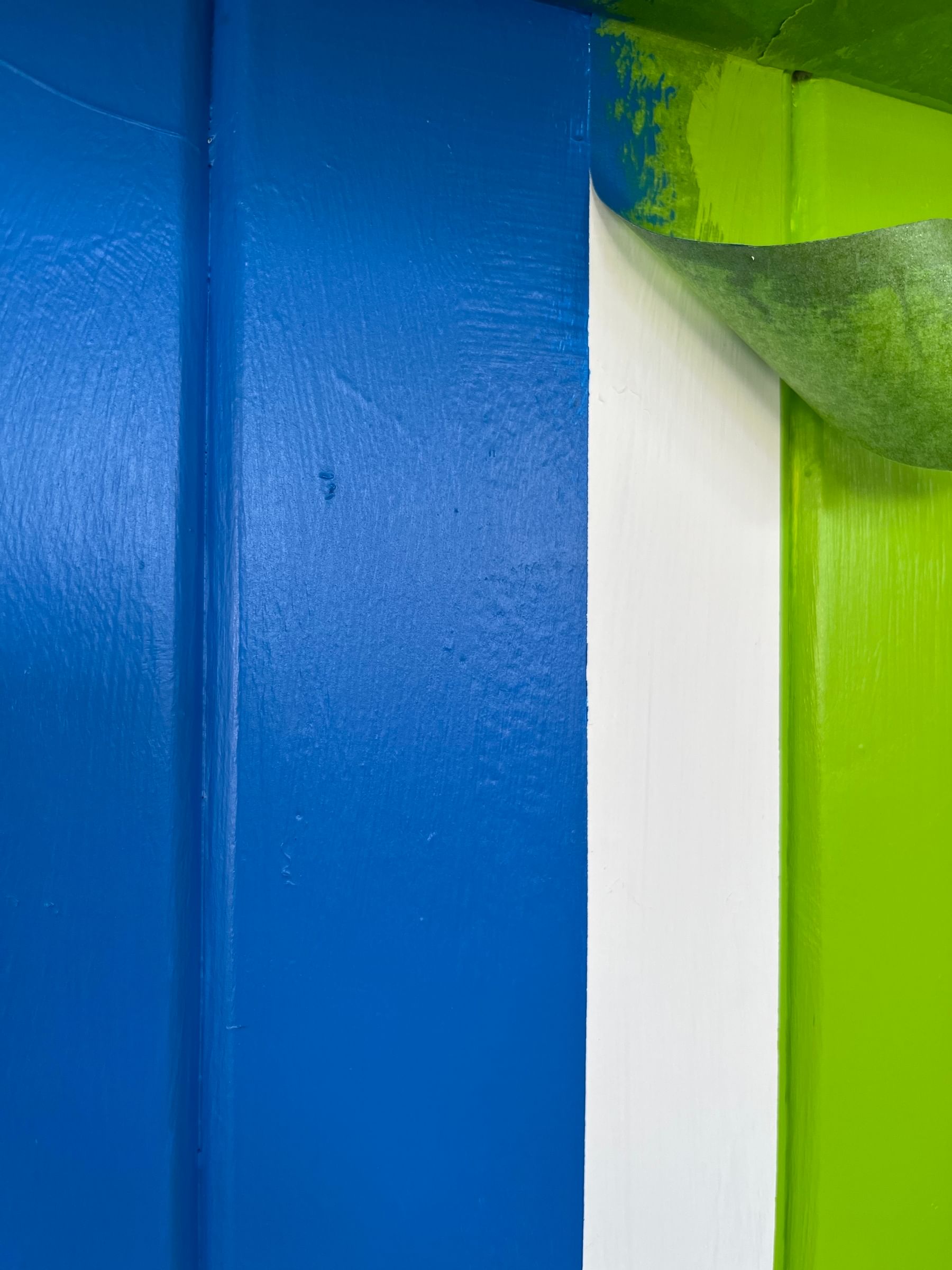 Blue and green section of a hutch with a green piece of FrogTape getting peeled off, revealing a crisp white line dividing the blue and green.