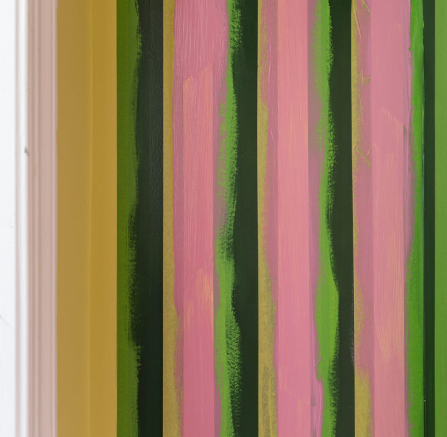 Yellow FrogTape Delicate Surface Painter's Tape lined vertically on a wall. The wall is painted with dark green and pink paint