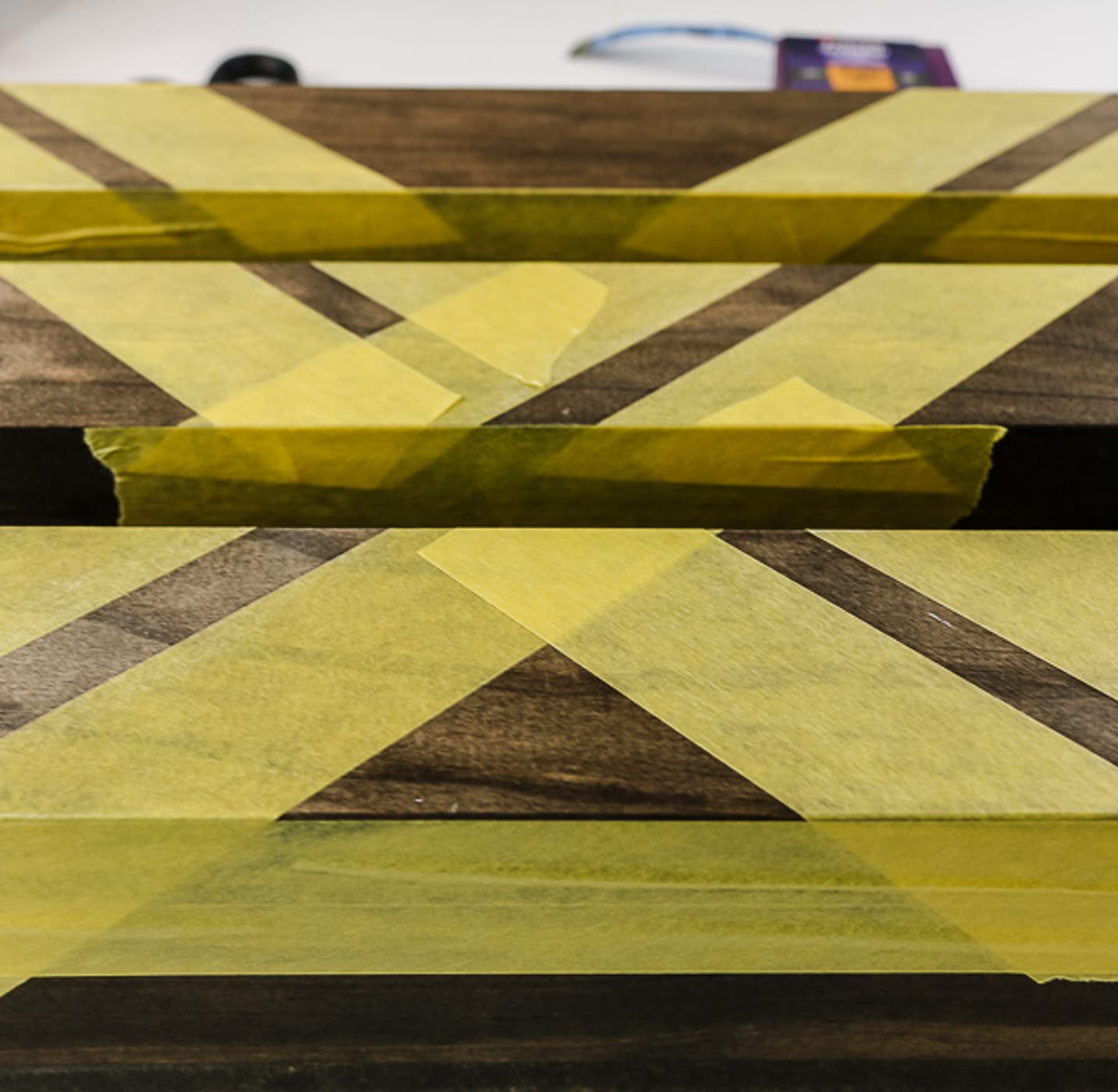 Yellow FrogTape Delicate Surface Painter's Tape taped across wooden shelves.