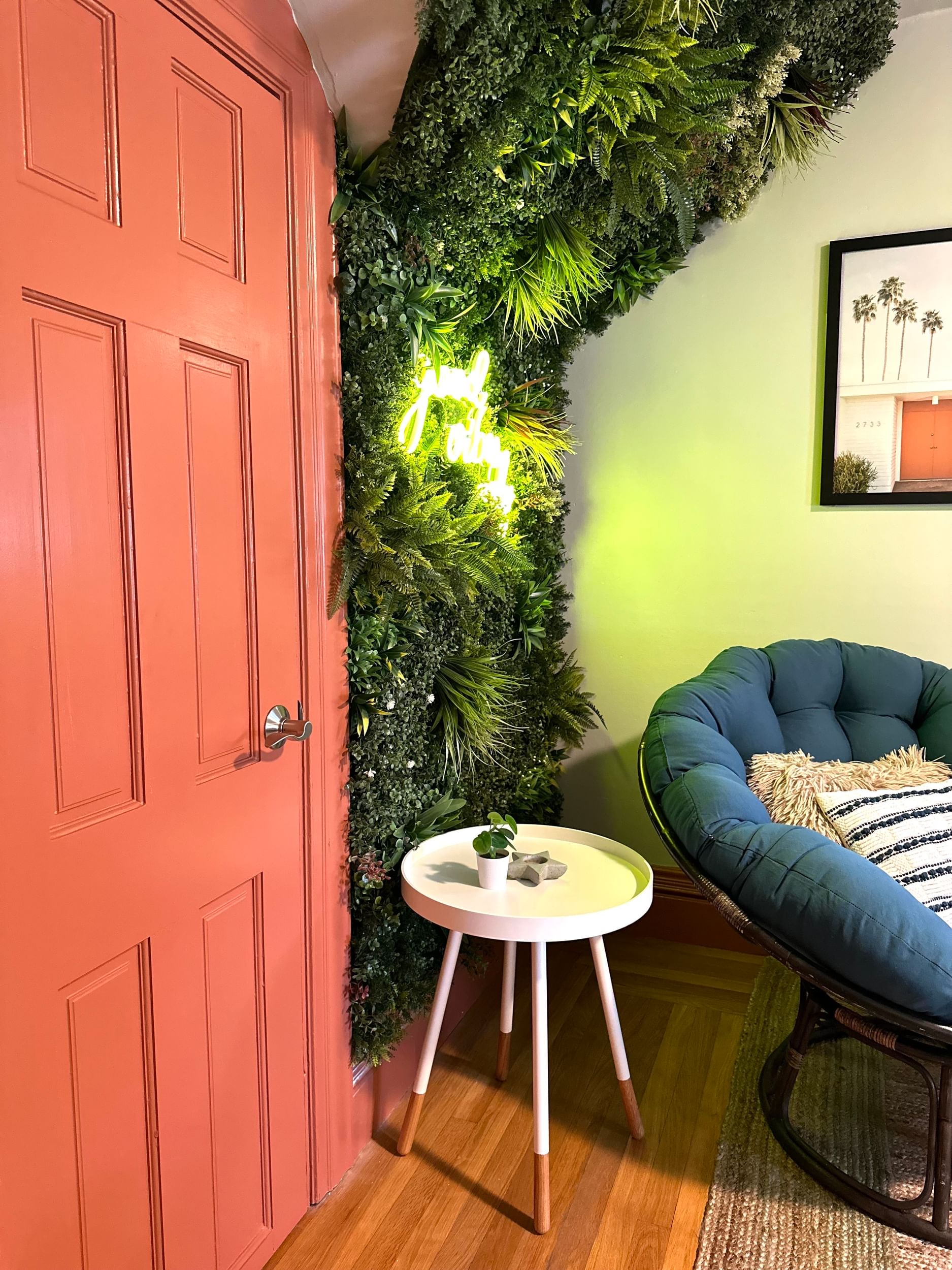 Interior orange painted door peaking into casual, bohemian sitting room