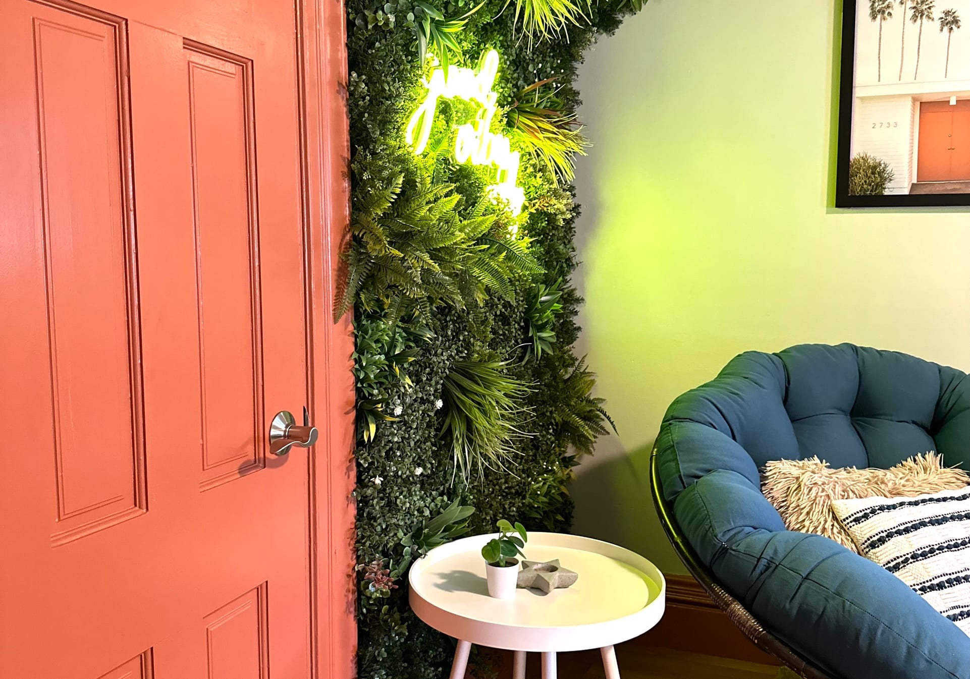 Interior orange painted door peaking into casual, bohemian sitting room