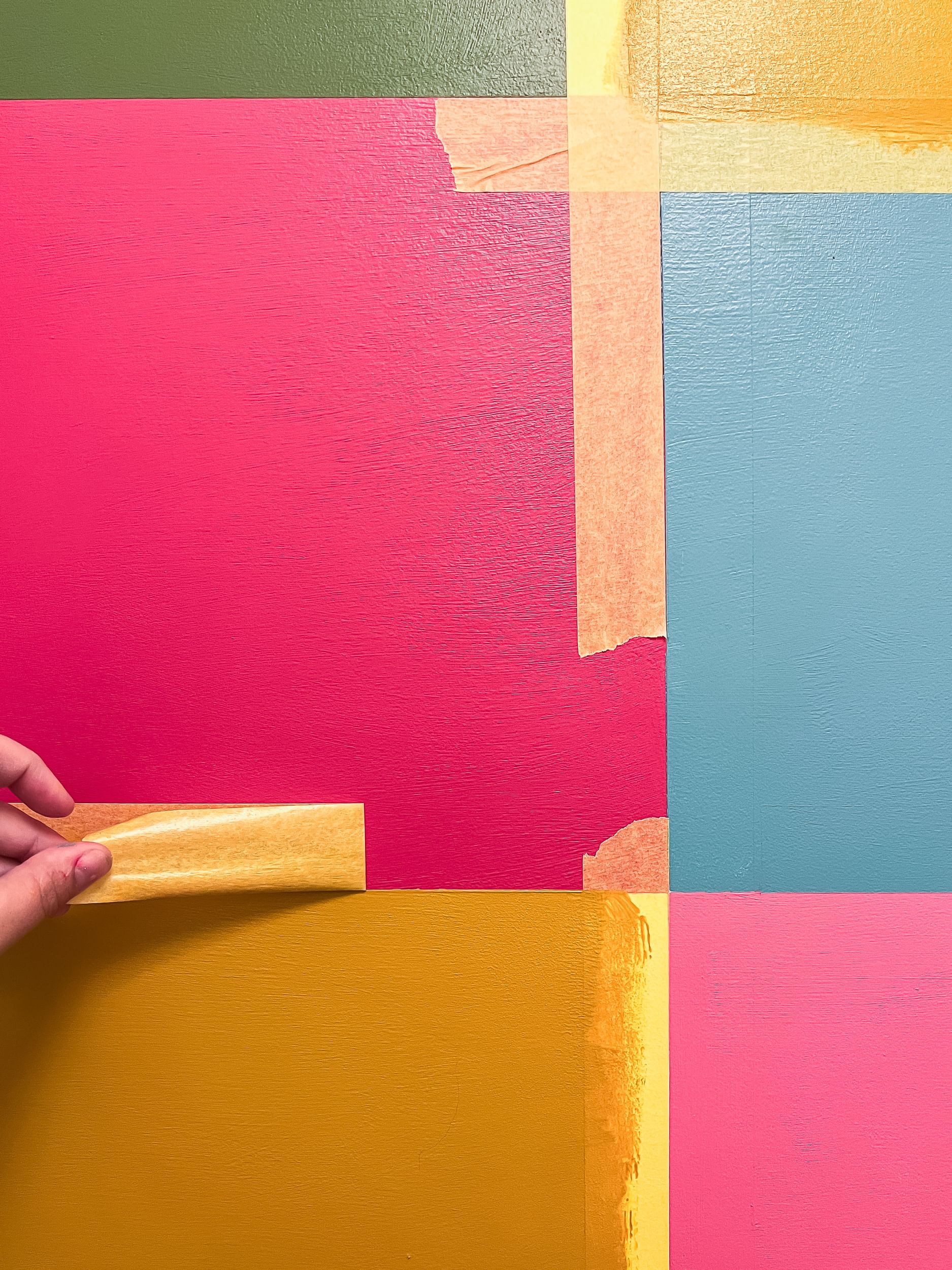 Yellow FrogTape Delicate Surface Painter's Tape being removed from a colorful wall of squares to reveal super crisp paint lines