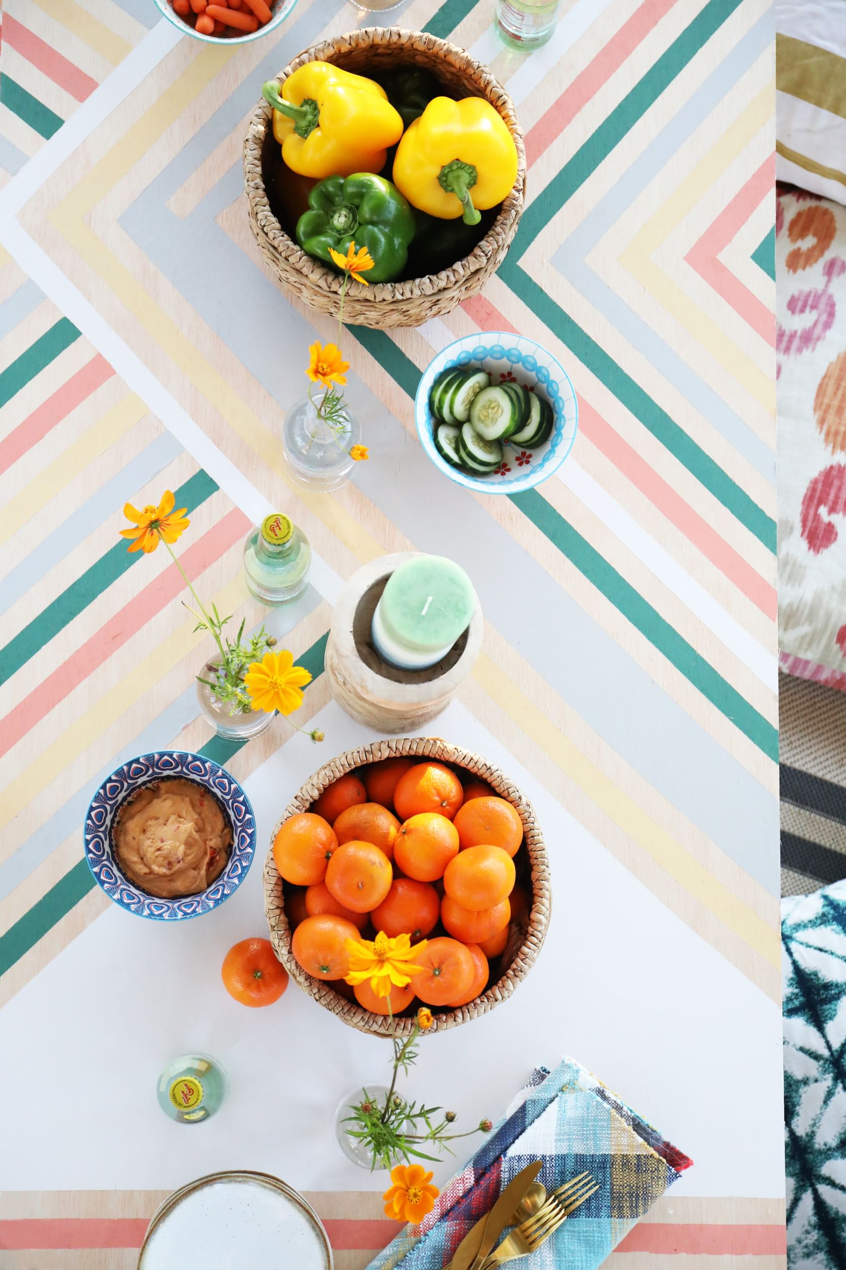 Table Painted with straight and angled lines, set with fruits and veggies in baskets