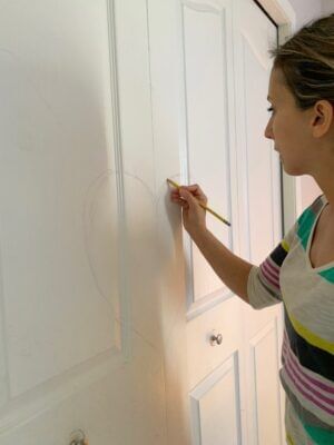 A woman marking with a pencil on closet doors