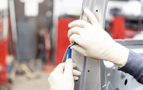 Gloved Hands using blue FrogTape to mask the inside of a car door