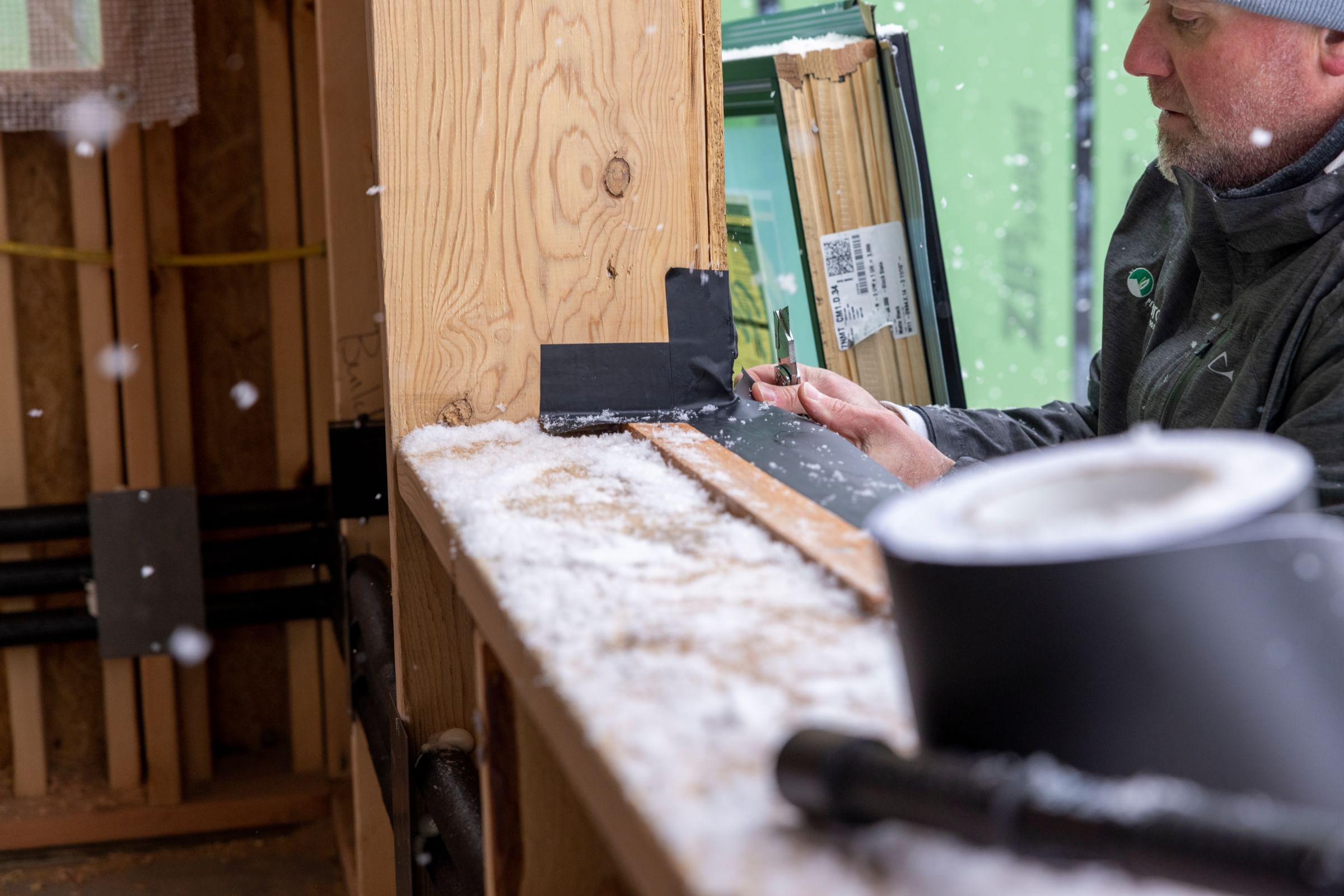 The construction of a new building using FrogTape Flashing Tape. There is a large opening for a window where a man is sealing the seams with Flashing Tape.