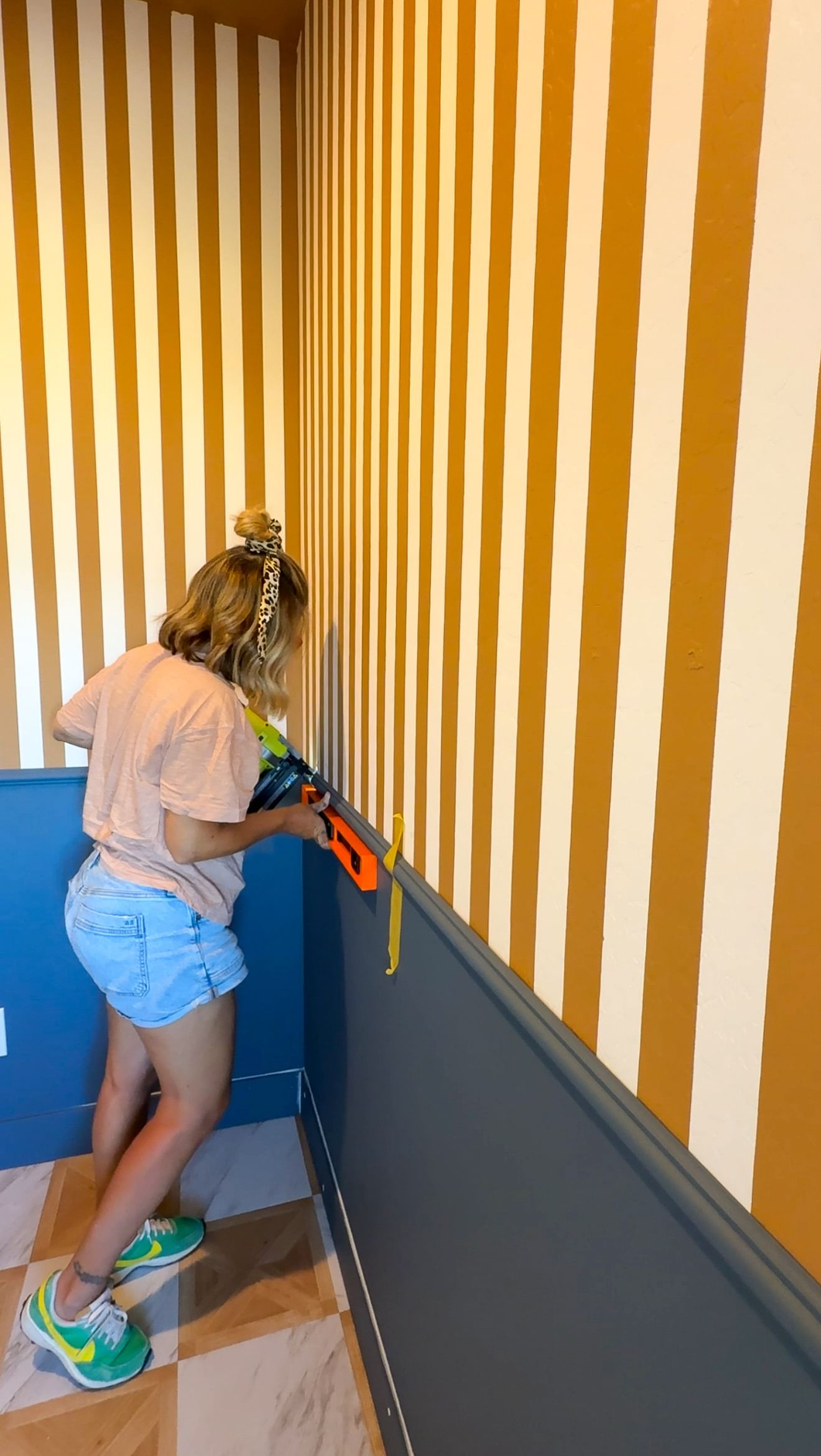 A woman nailing trim to the mid section of a wall