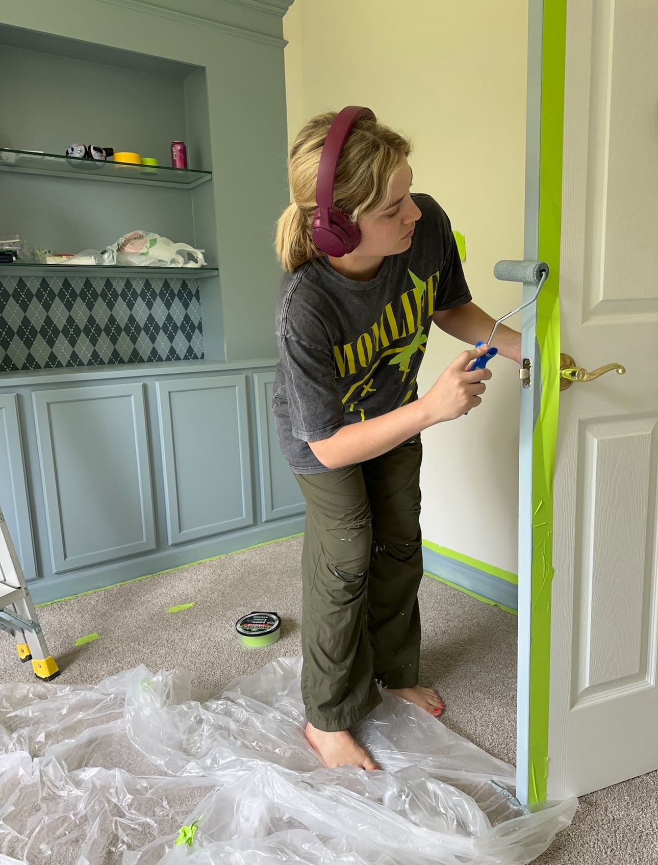 Woman painting the inside of a door blue with a paint roller