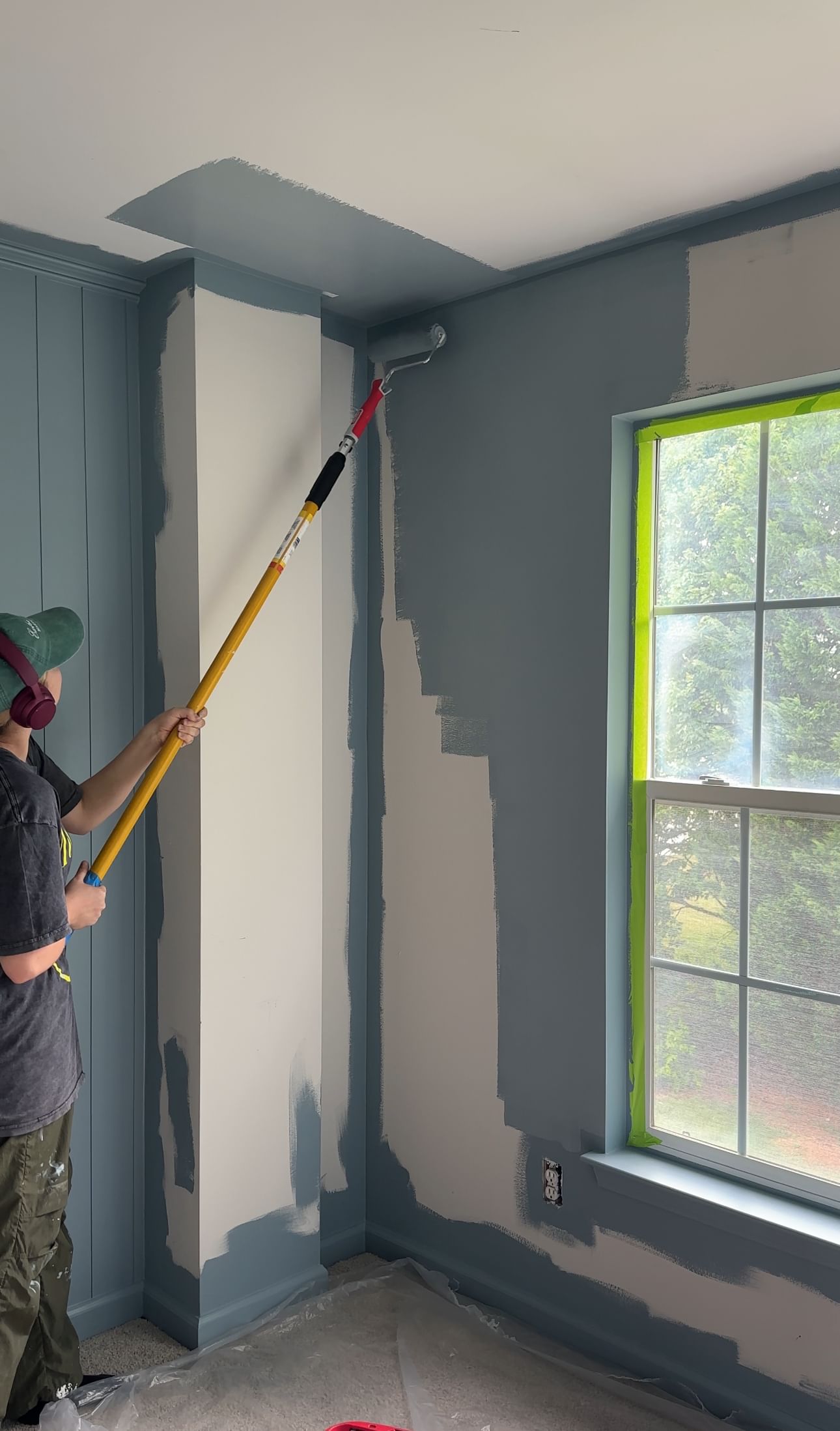 Woman using a paint roller to paint a room blue