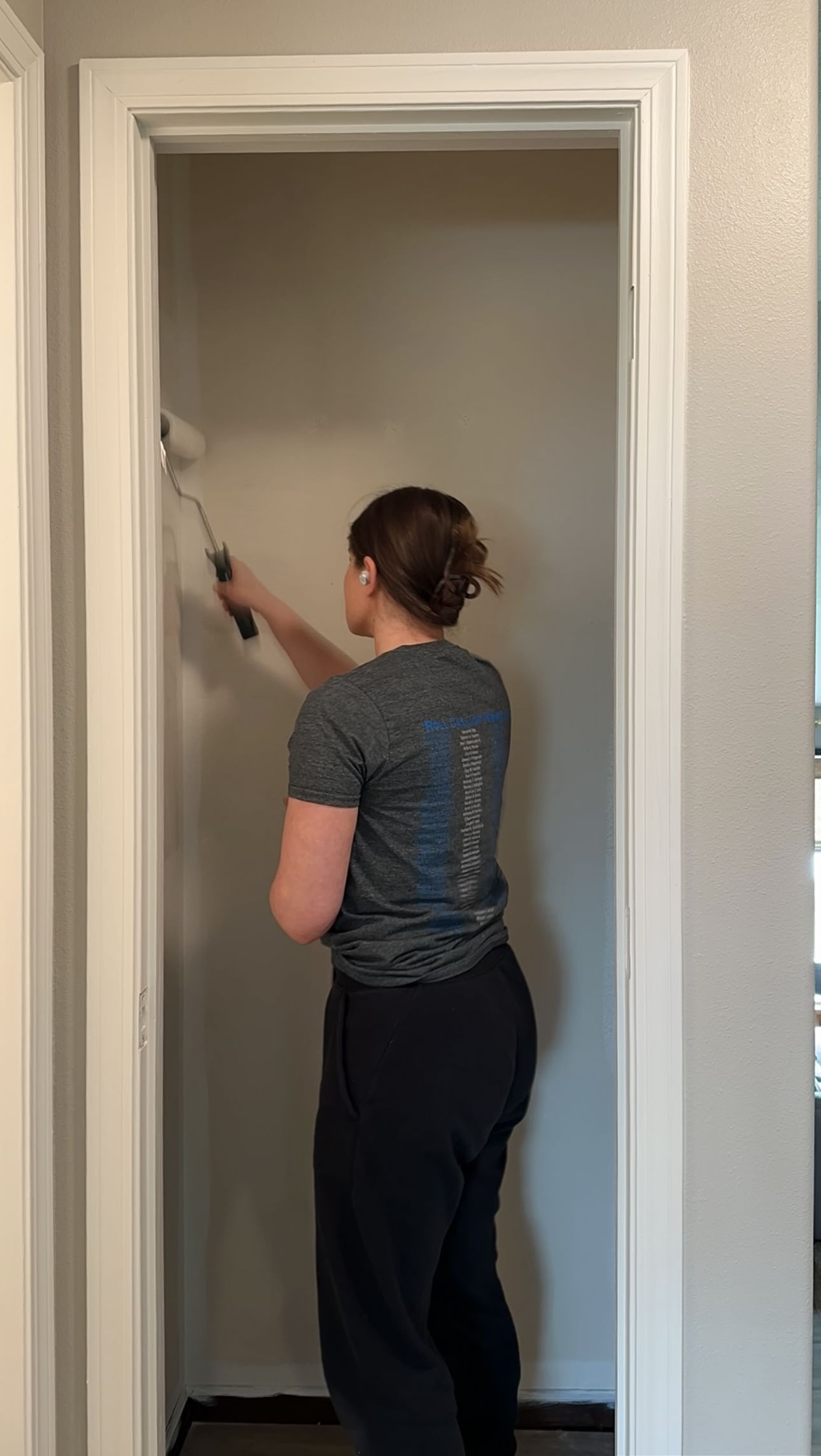 Woman using a paint roller to paint the inside of a closet white